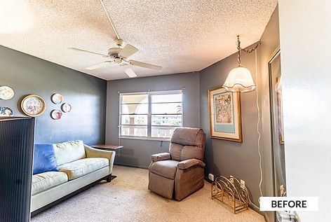Room with gray walls, sofa, recliner, ceiling fan, and window; “BEFORE” text in corner.