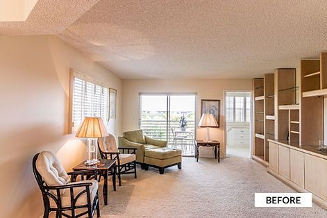 Living room with beige walls and carpet, a green chaise lounge, and built-in shelving.