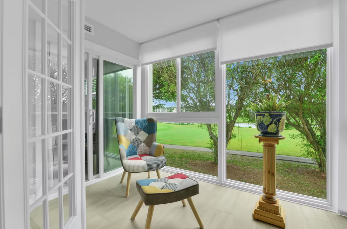 Modern white house with a pool, black roof with solar panels, and large windows.