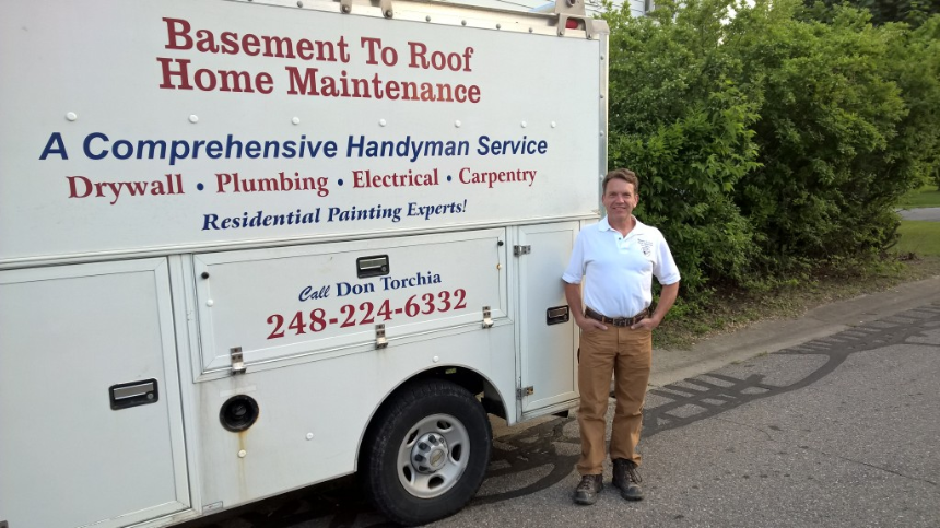 A man standing in front of a basement to roof home maintenance truck