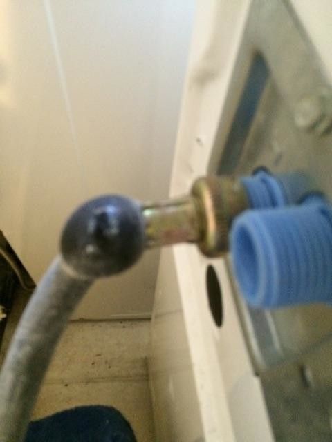 A close up of a hose attached to a washing machine.