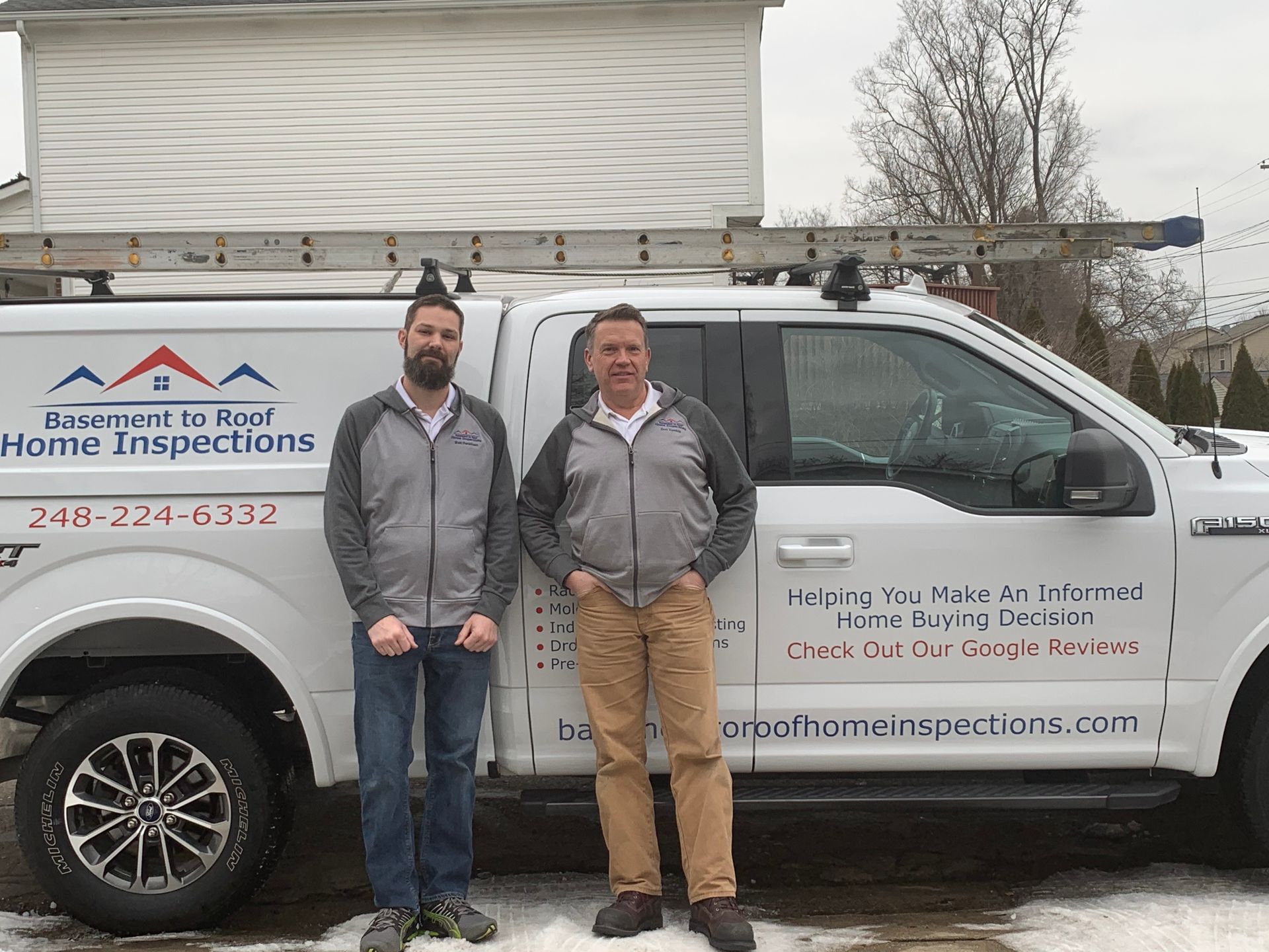 Two men are standing in front of a white truck.