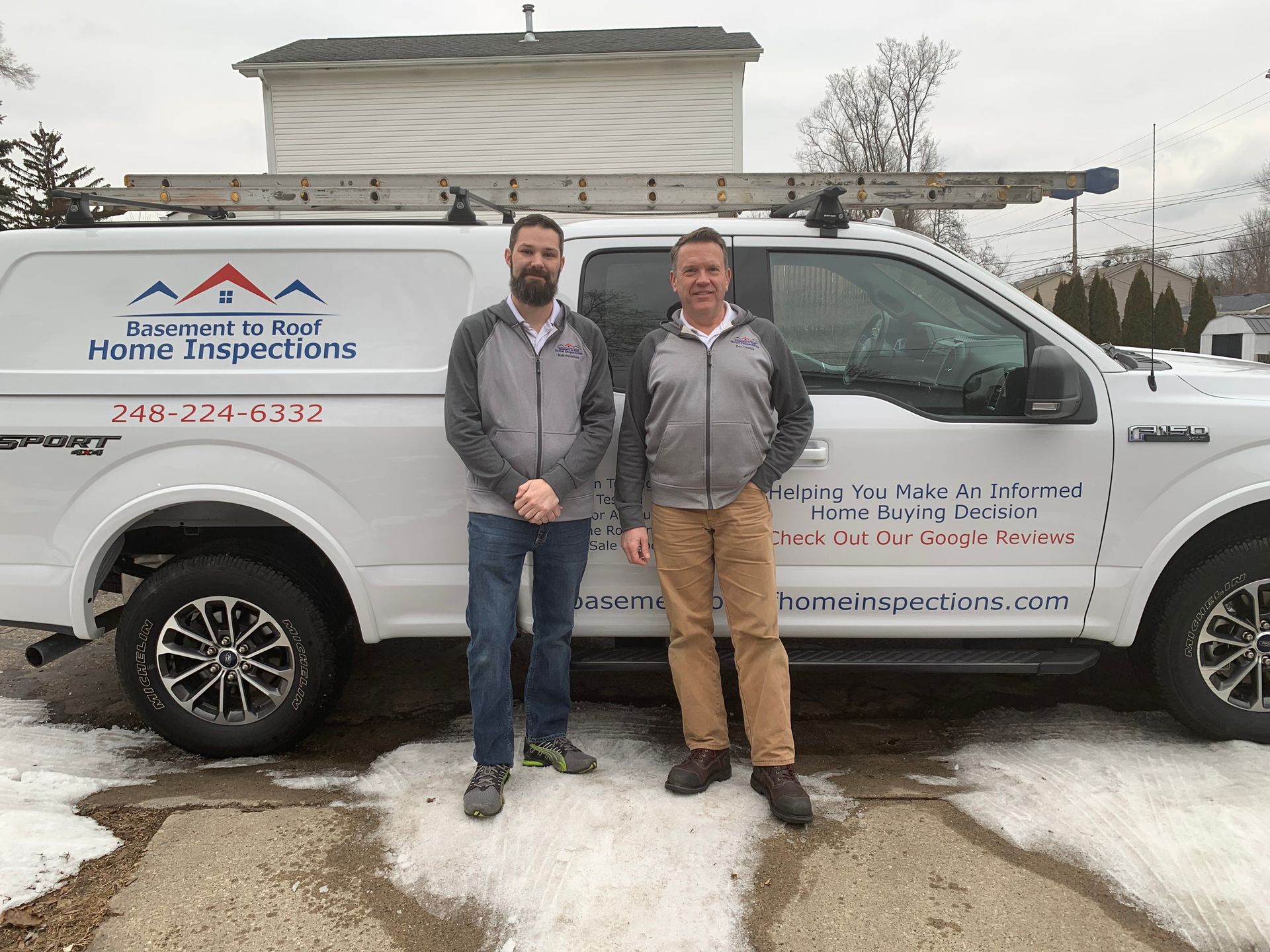 Two men are standing in front of a white van.