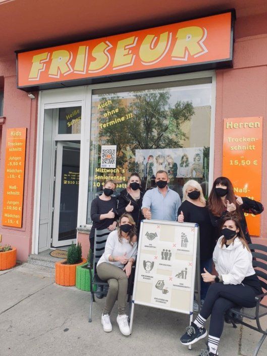 Eine Gruppe von Menschen steht vor einem Friseur