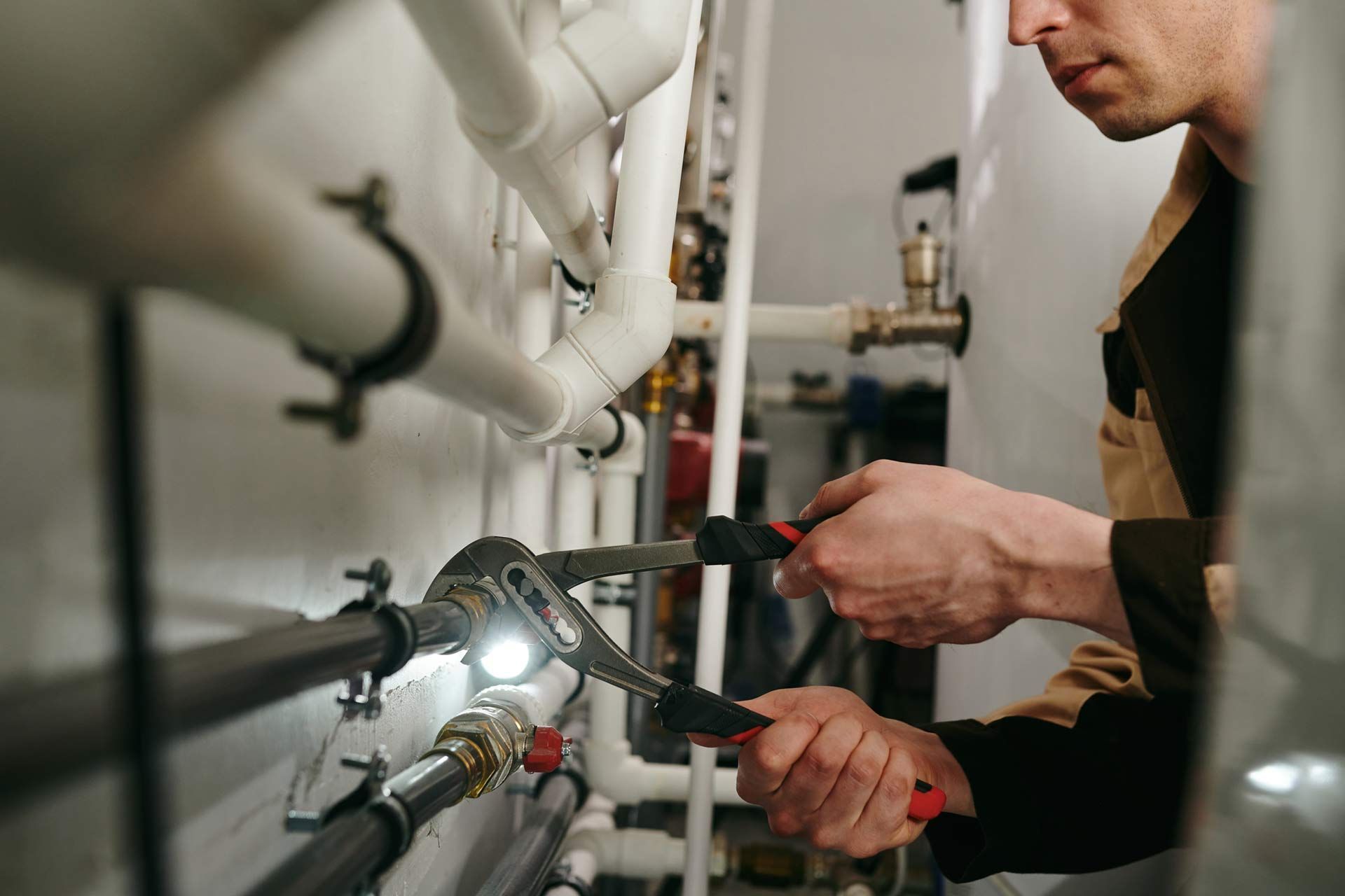 A commercial plumbing contractor using a tool to fix parts of pipes during work. A commercial plumbing contractor using a tool to fix parts of pipes during work.