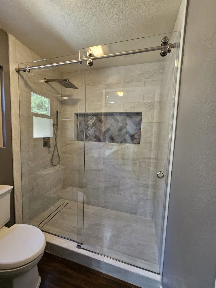 Modern bathroom with a glass sliding shower door, tiled walls, and a built-in niche.
