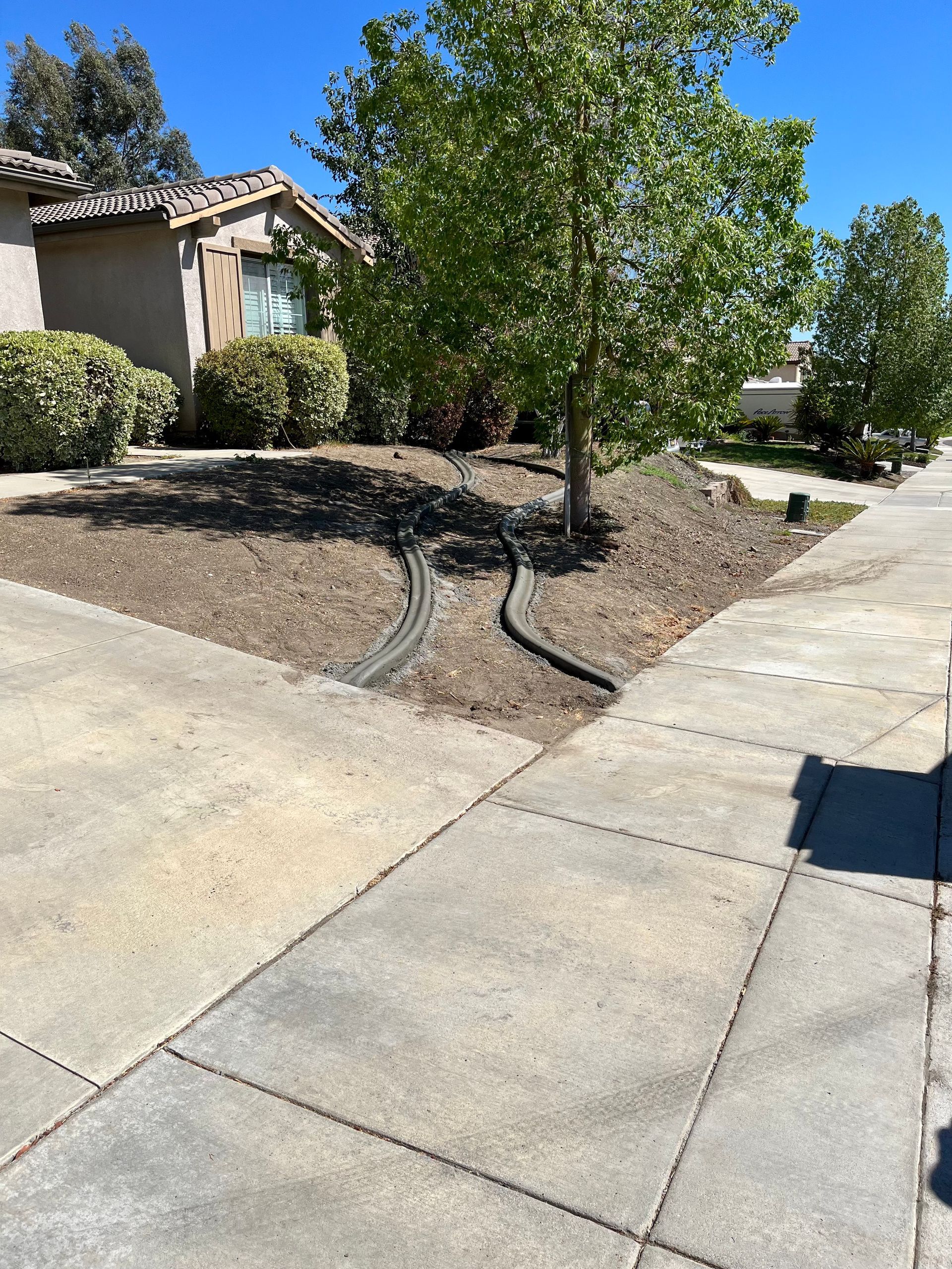 a hose is laying on the sidewalk in front of a house .