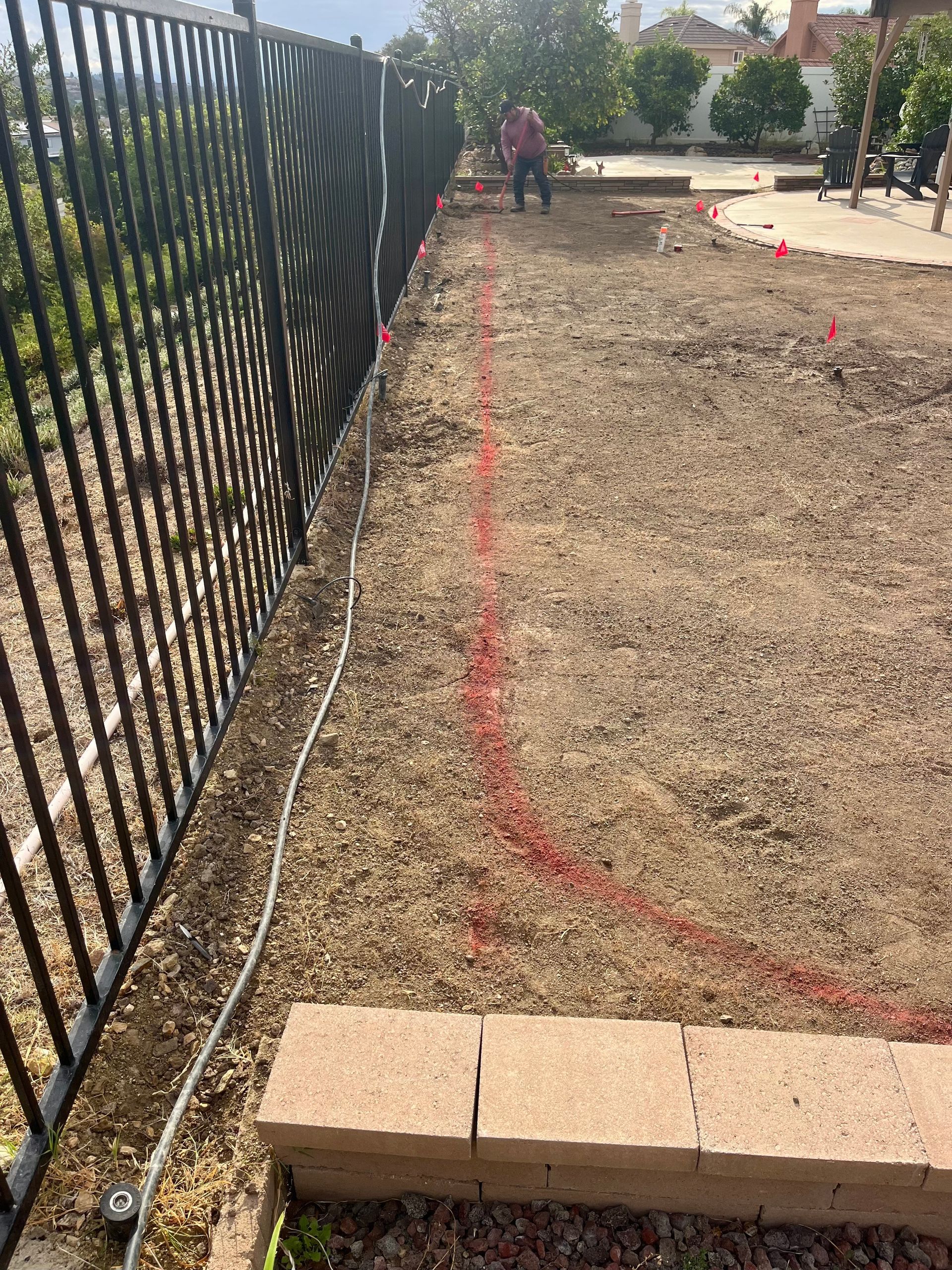 A person is standing in the dirt next to a fence.