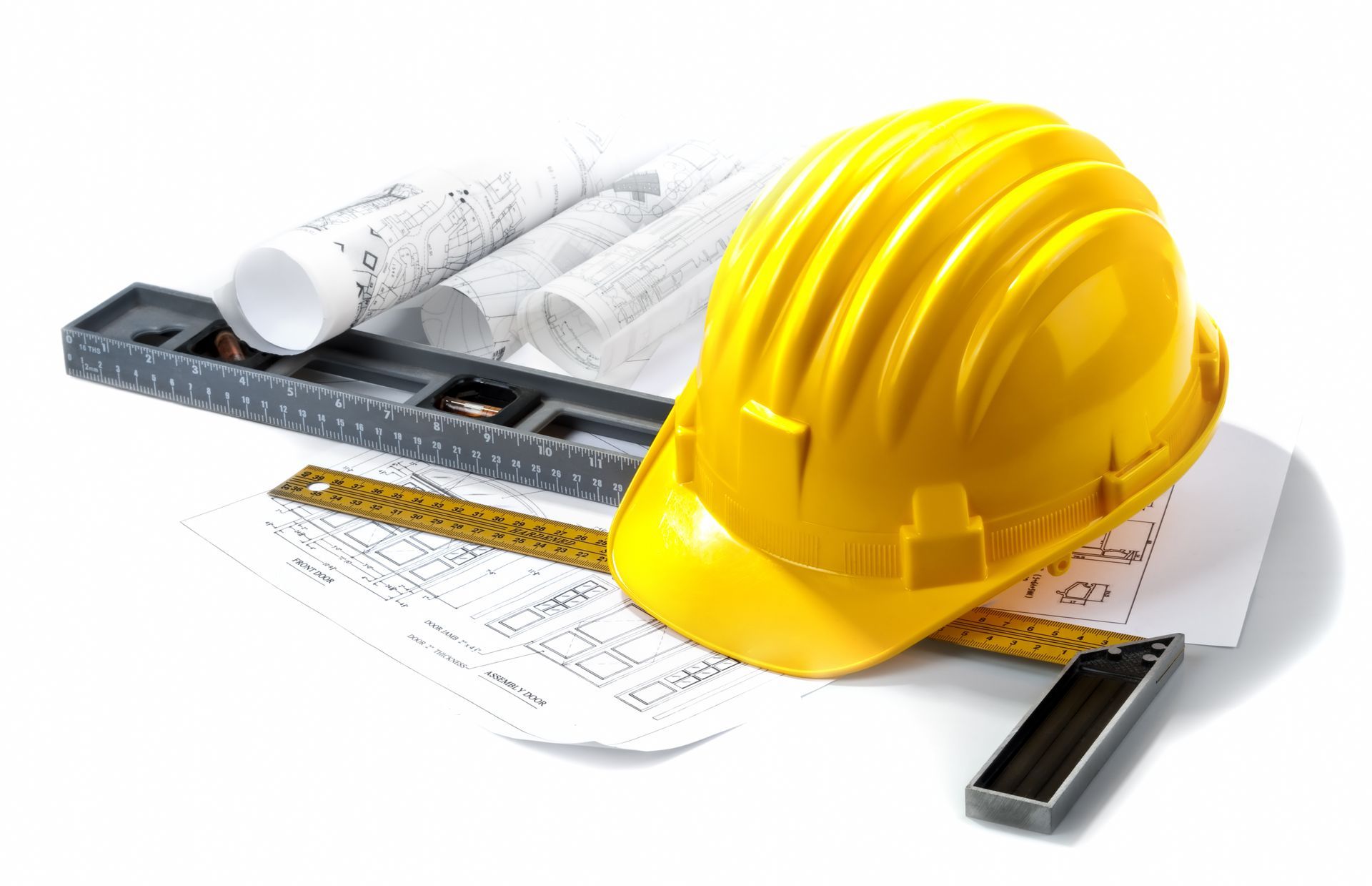 Yellow hard hat on architectural blueprints with tools