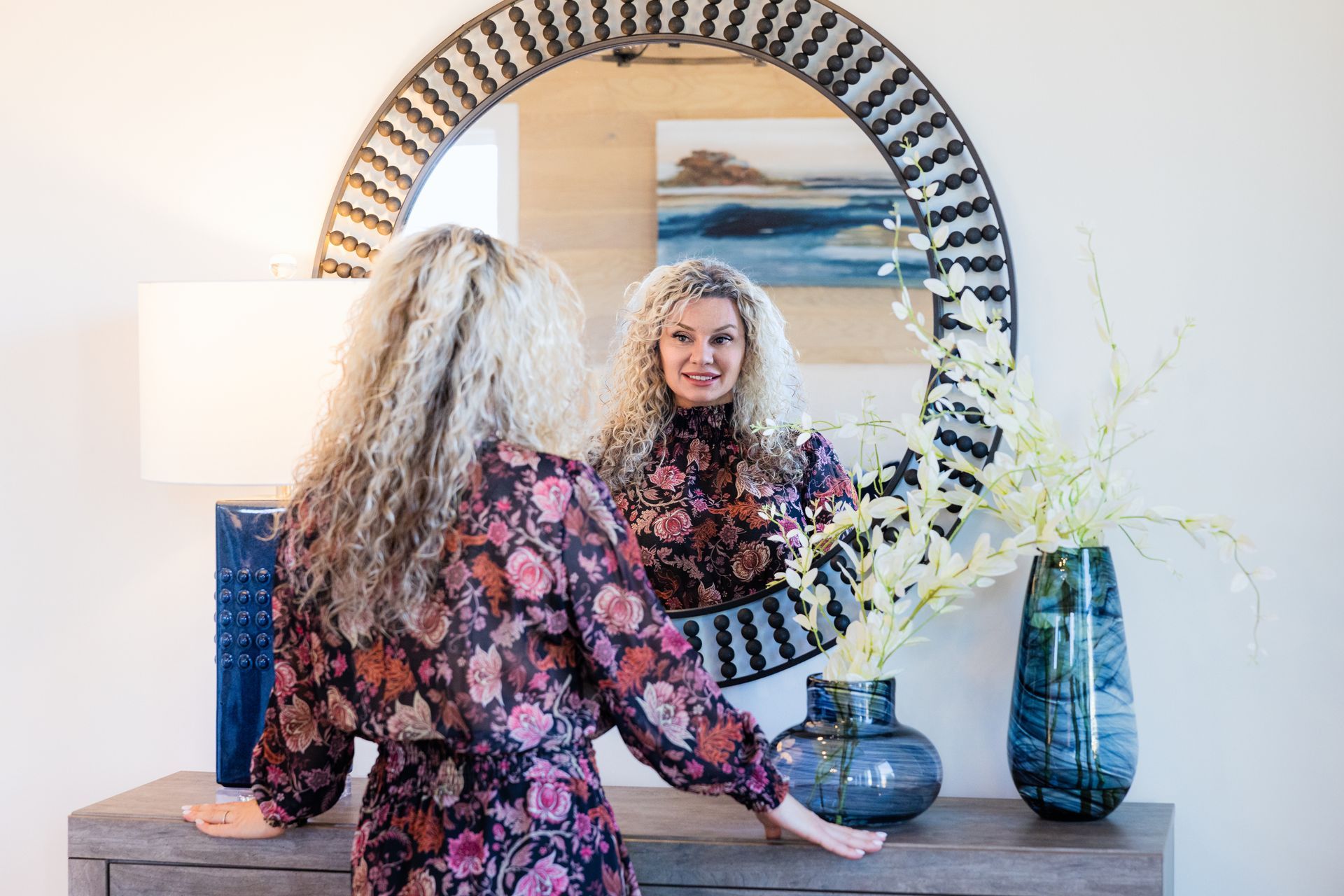 A woman is looking at her reflection in a mirror.