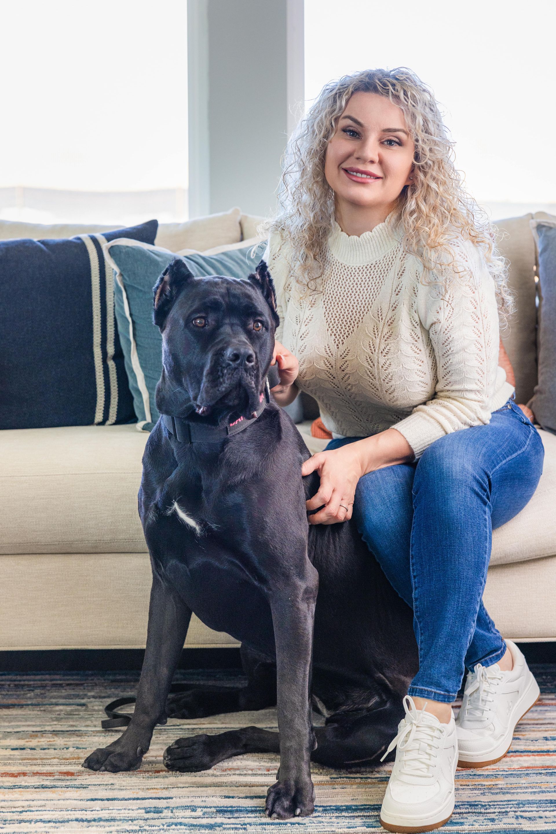 A woman is sitting on a couch with a dog.
