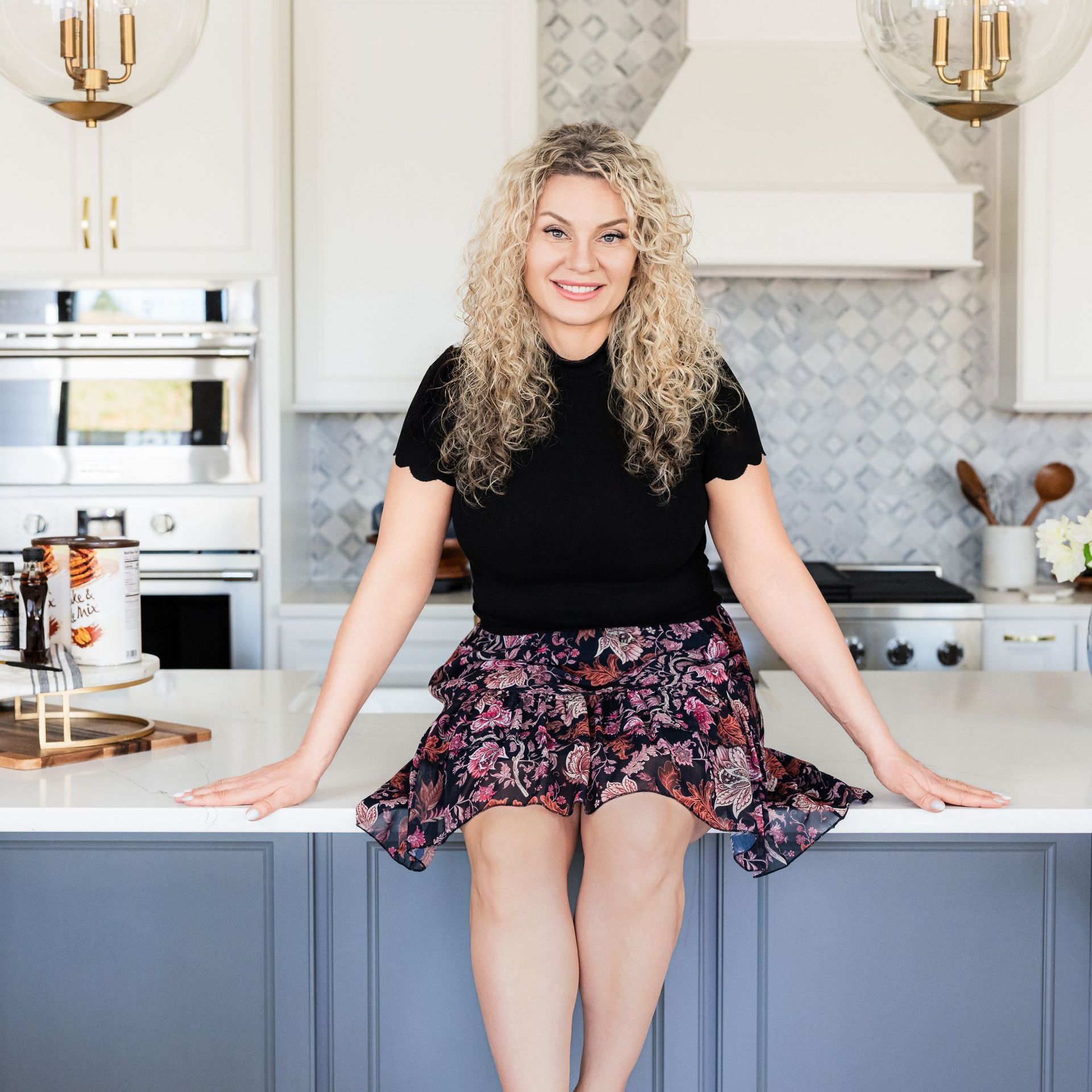 A woman is sitting on a kitchen counter with her legs crossed