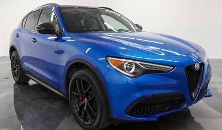 Blue Alfa Romeo Stelvio SUV with black wheels, parked indoors.