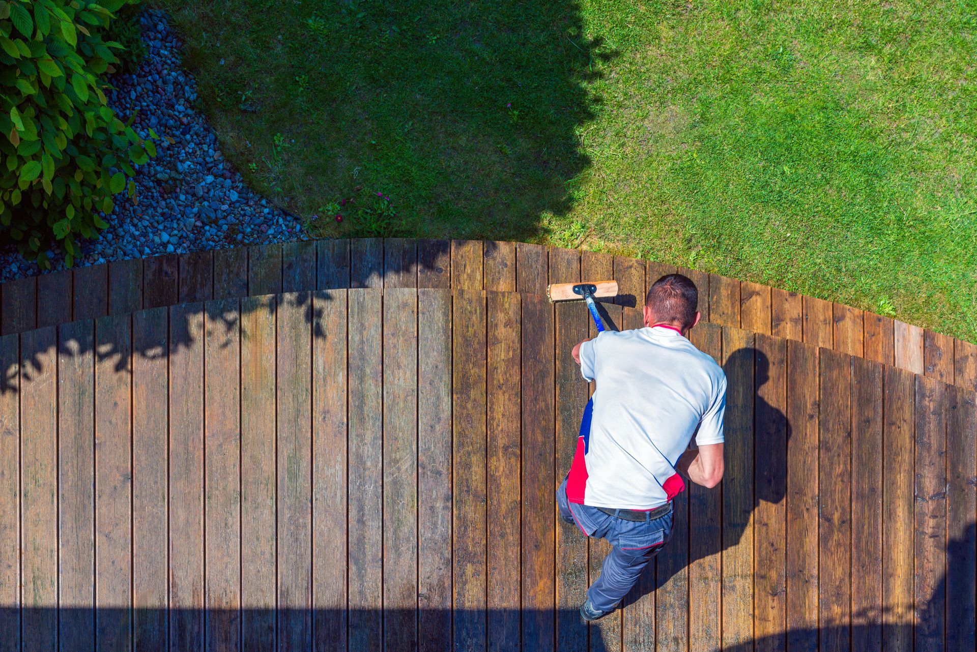 A man is cleaning a wooden deck with a broom.
