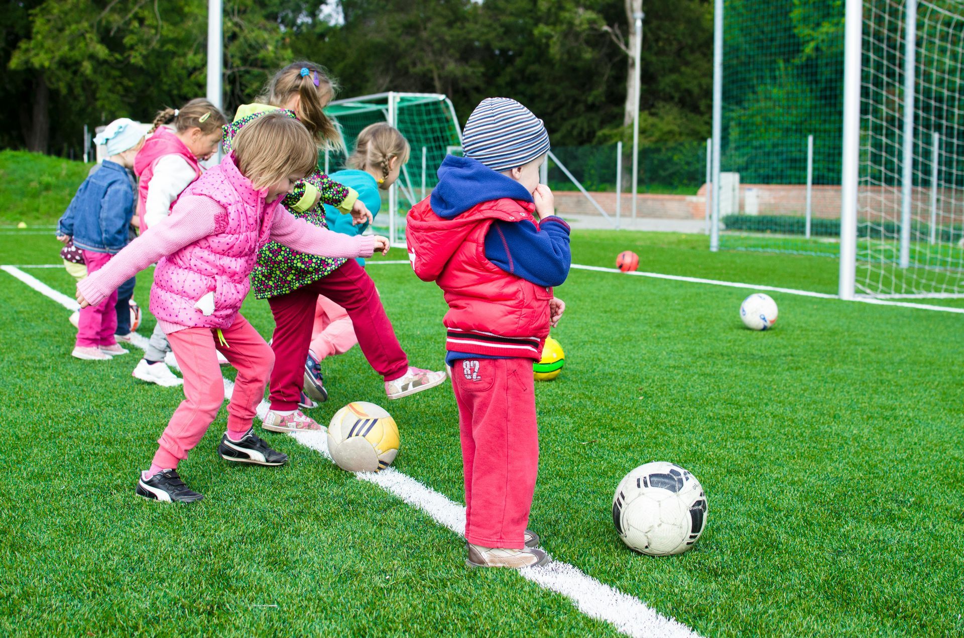 A group of children are playing with soccer balls on a field.