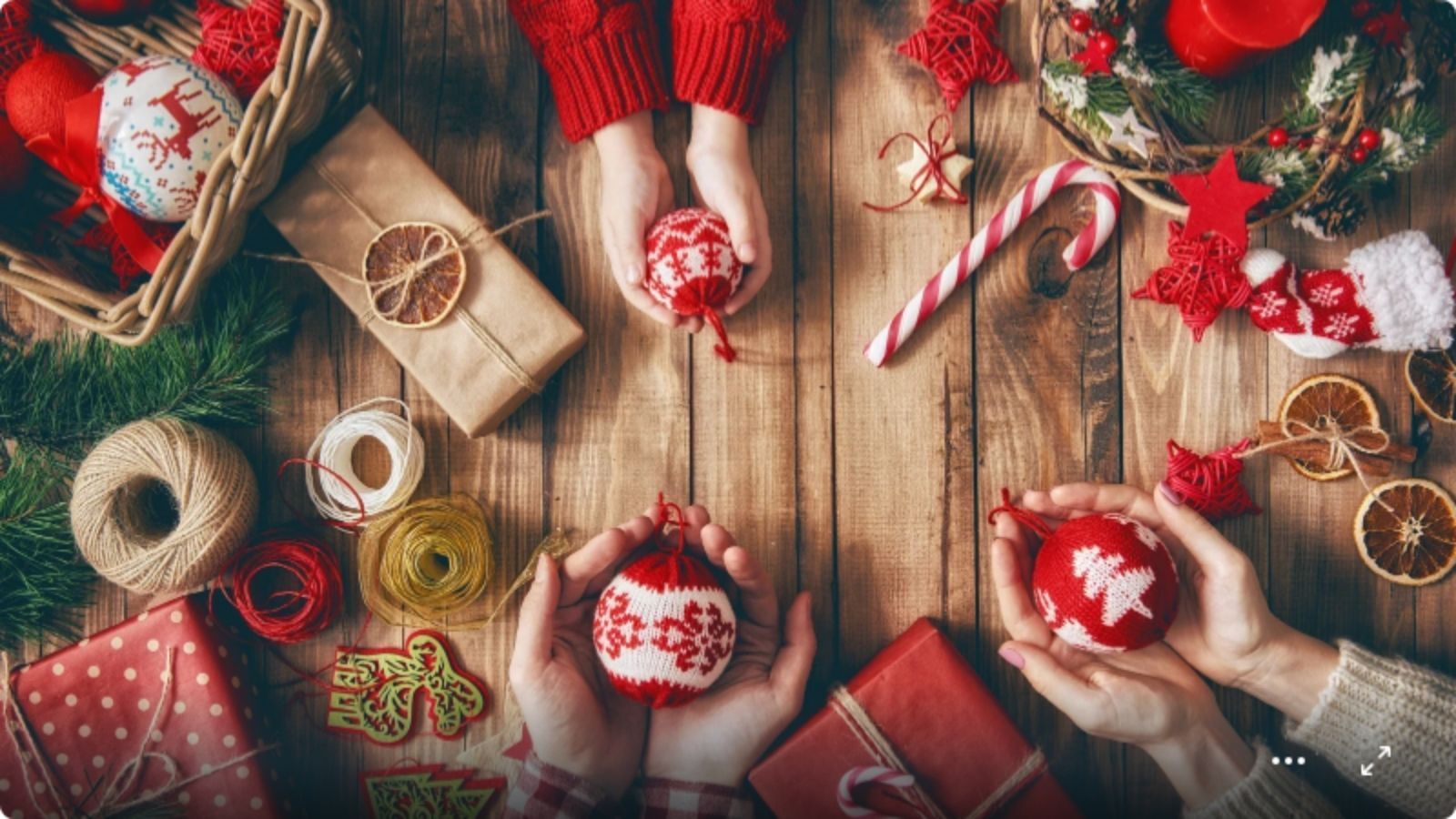 Hyggelig julebilde med hender som holder strikkede julekuler.