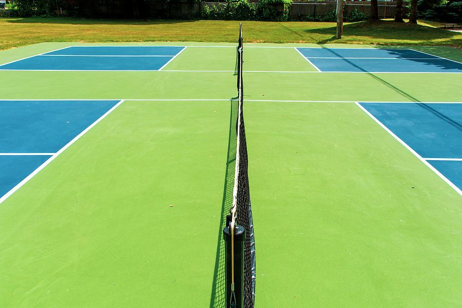 a green and blue tennis court with a black net