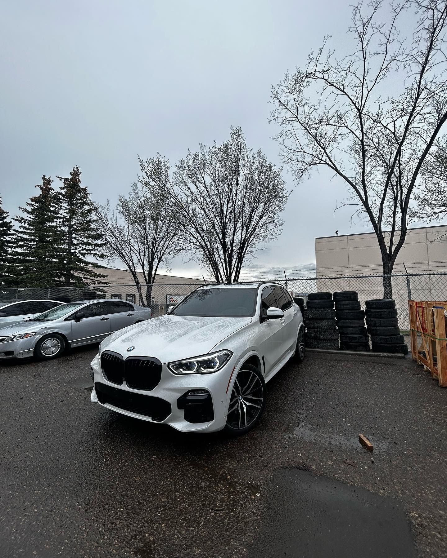 White BMW SUV Parked on Wet Pavement Near Trees | Economy Auto Repair