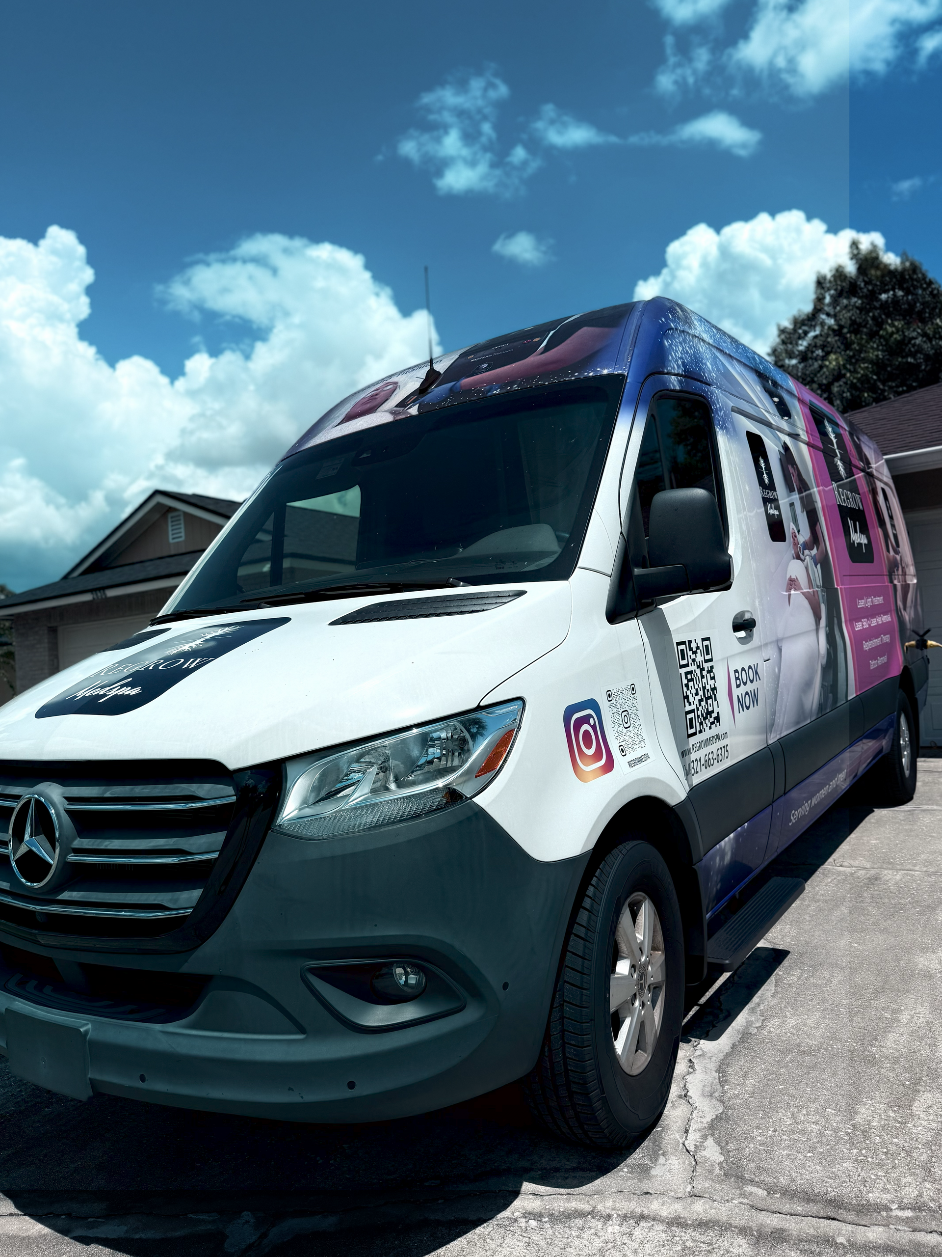 White Mercedes van with colorful graphics parked in a driveway on a sunny day.
