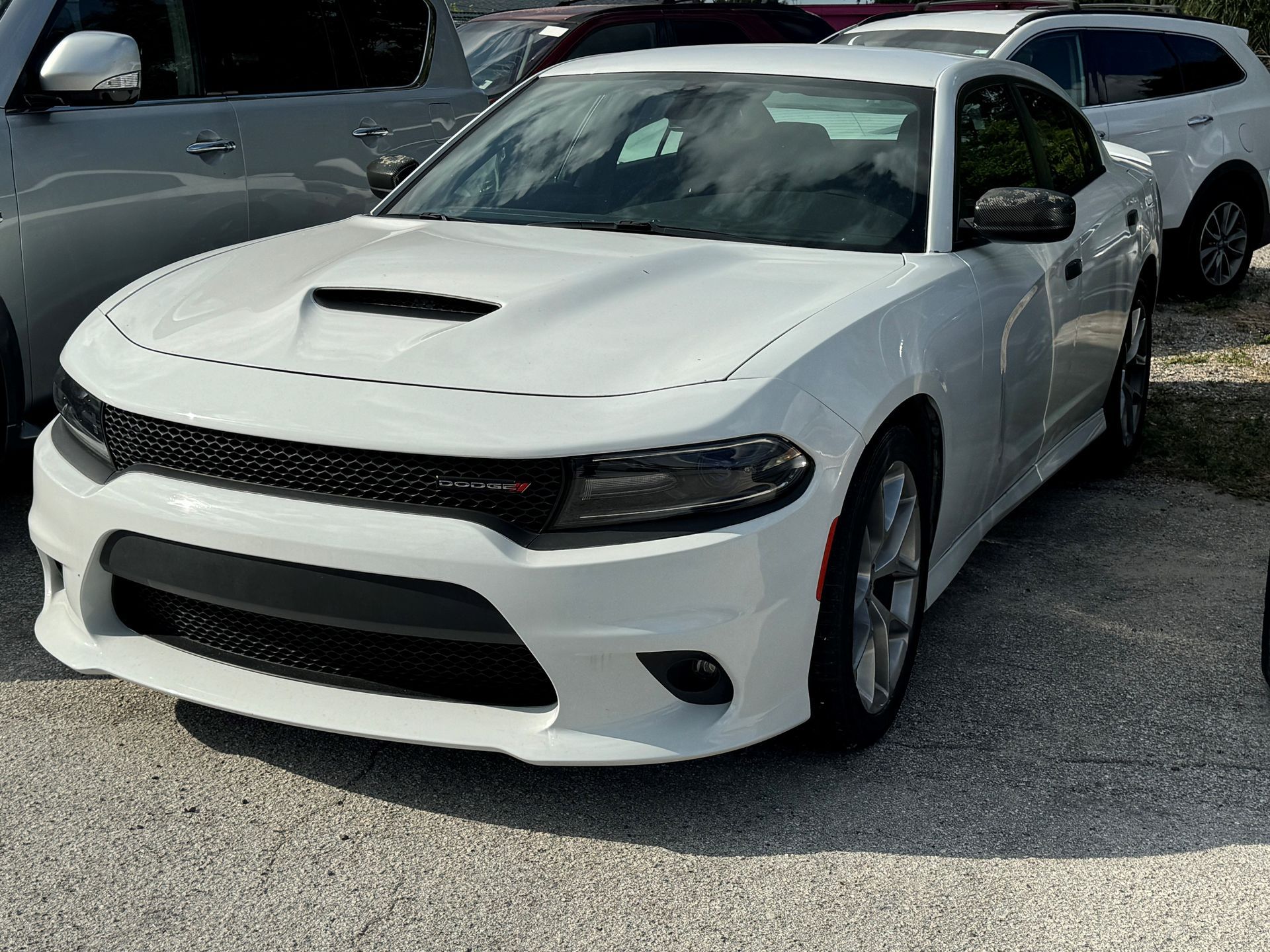 A white dodge charger is parked in a parking lot.