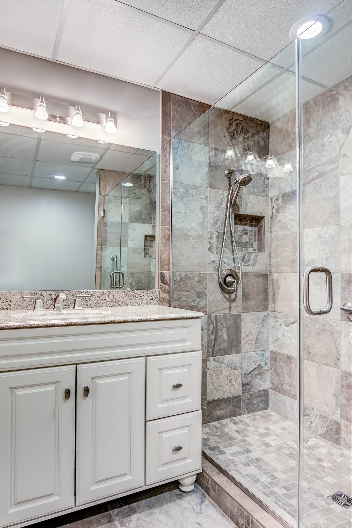 A bathroom with a walk in shower , sink and mirror.