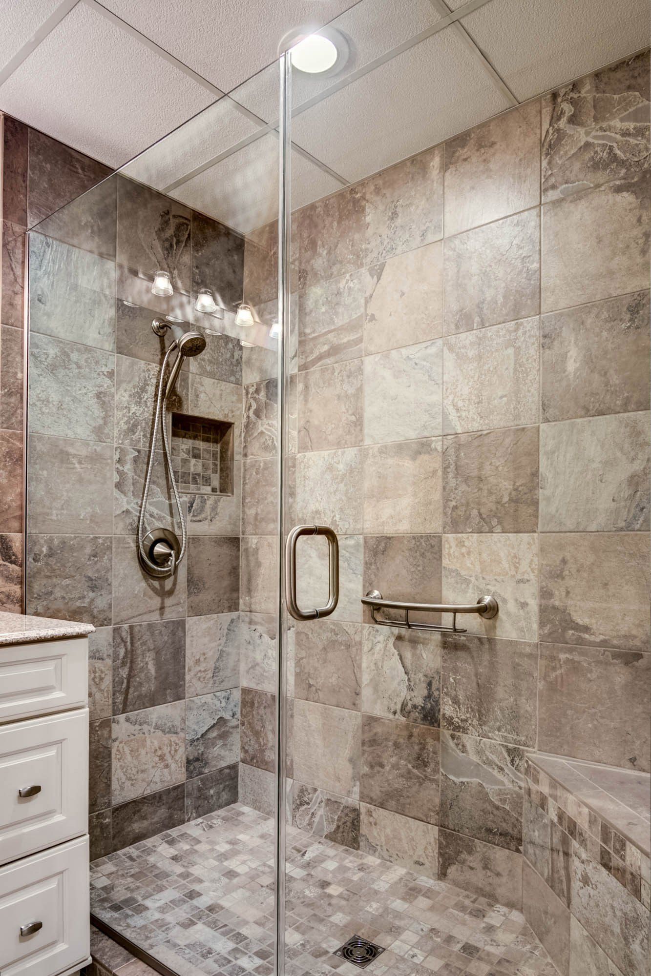 A bathroom with a walk in shower with a glass door.