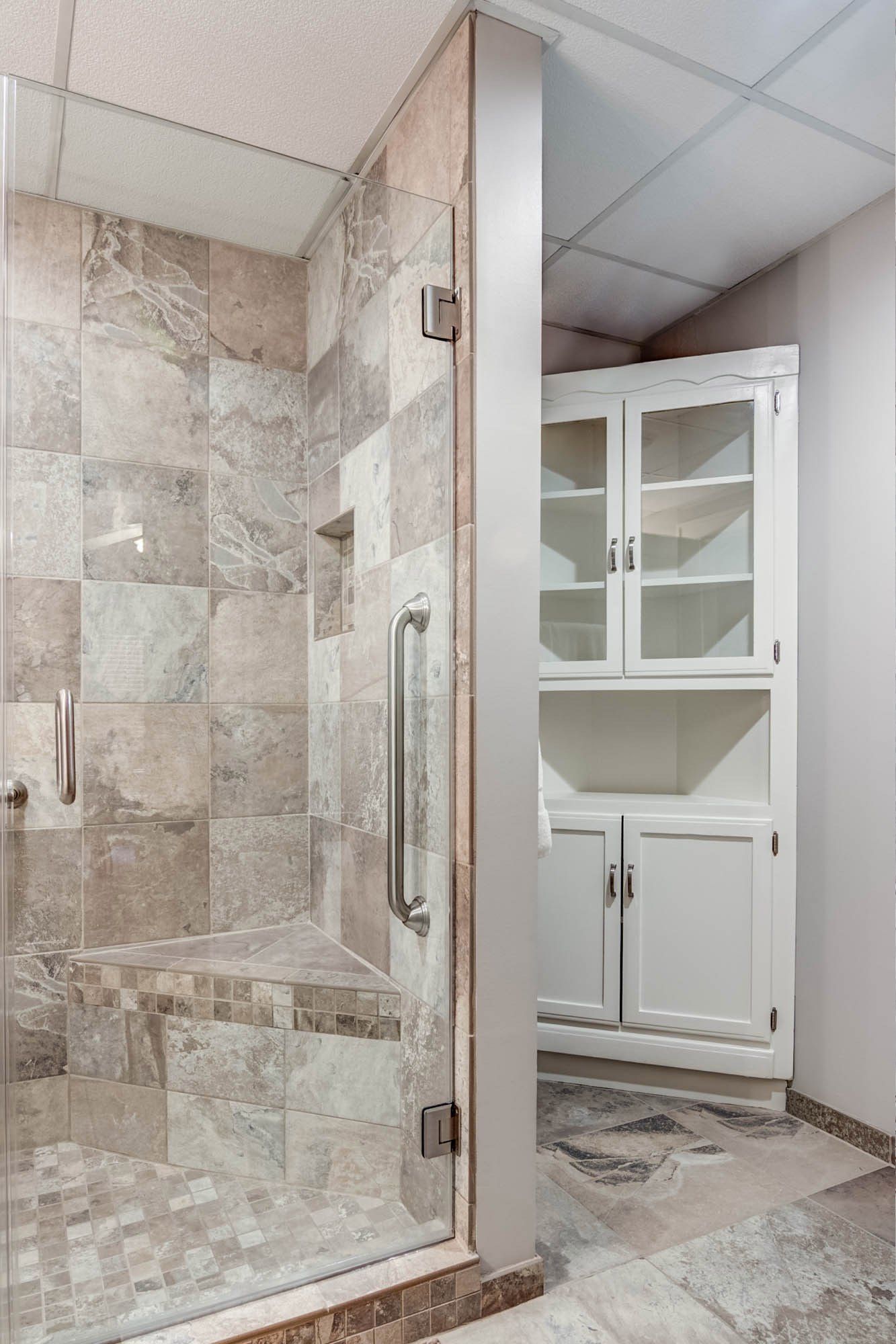 A bathroom with a walk in shower and a cabinet.