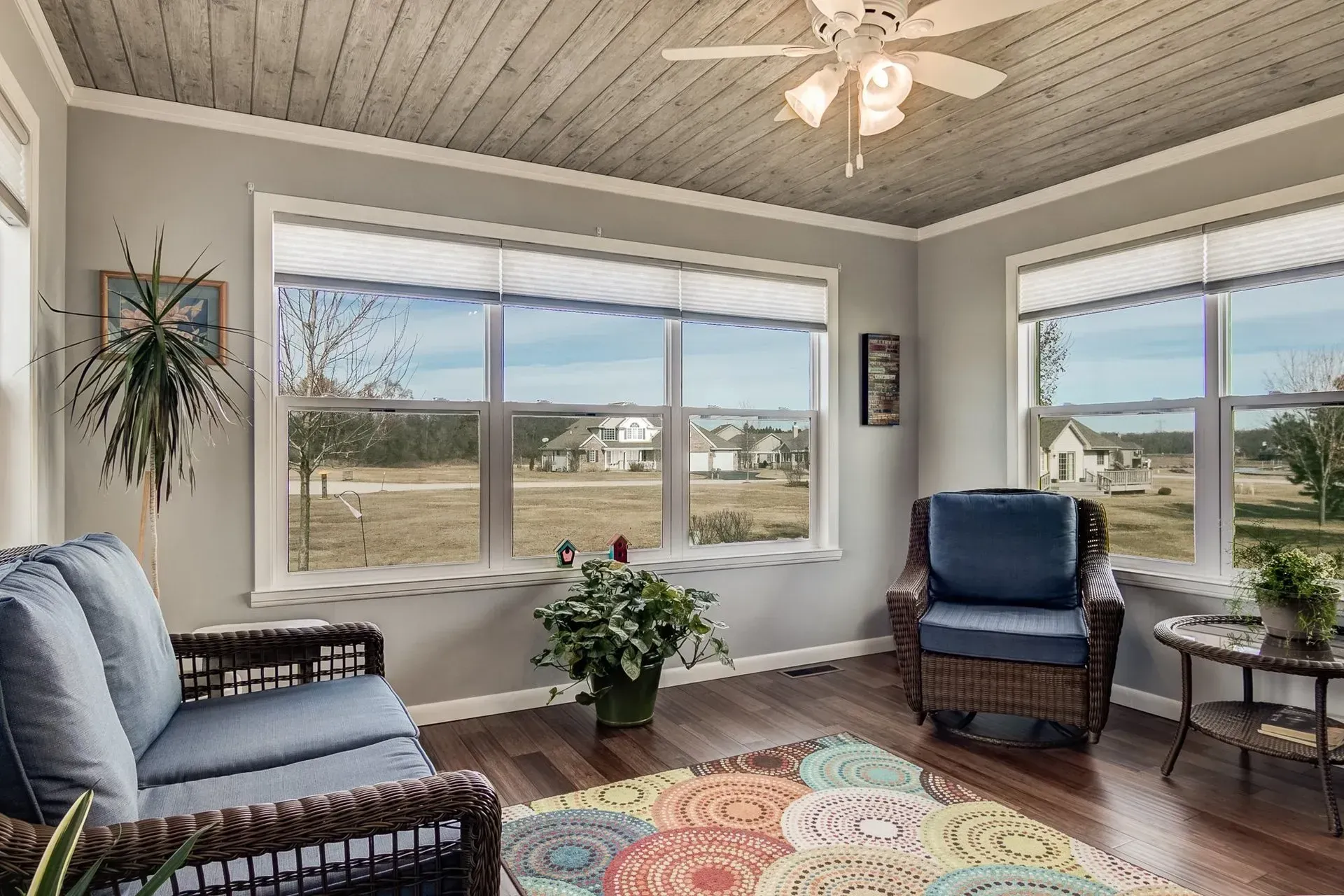 A living room with a couch , chair , table and ceiling fan.