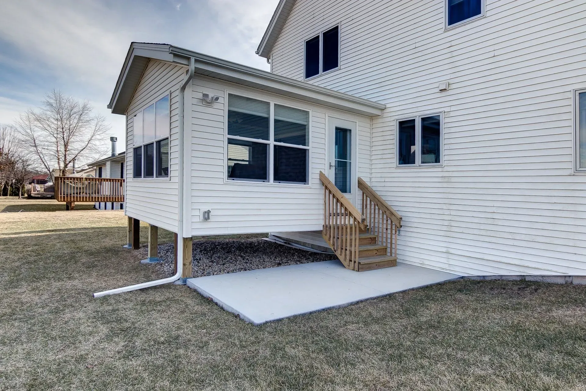 The back of a white house with a porch and stairs.