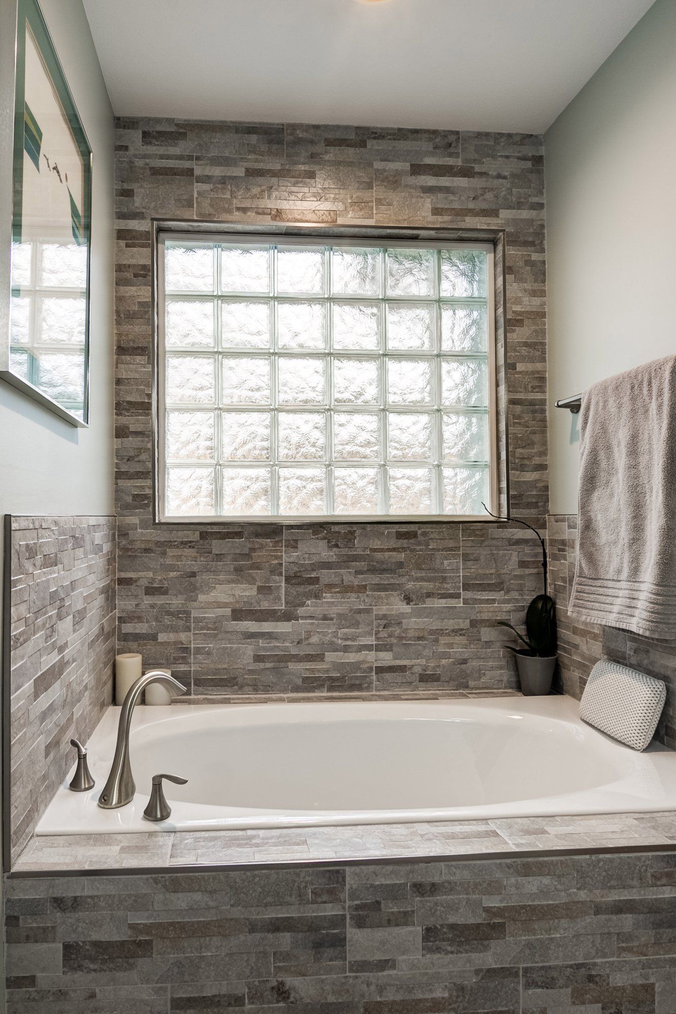 A bathroom with a tub and a window with glass blocks.