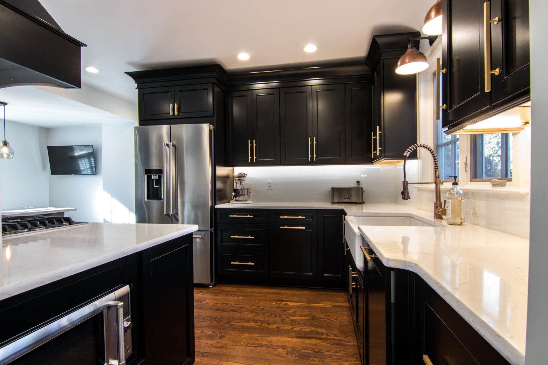A kitchen with black cabinets , stainless steel appliances , a sink , and a refrigerator.
