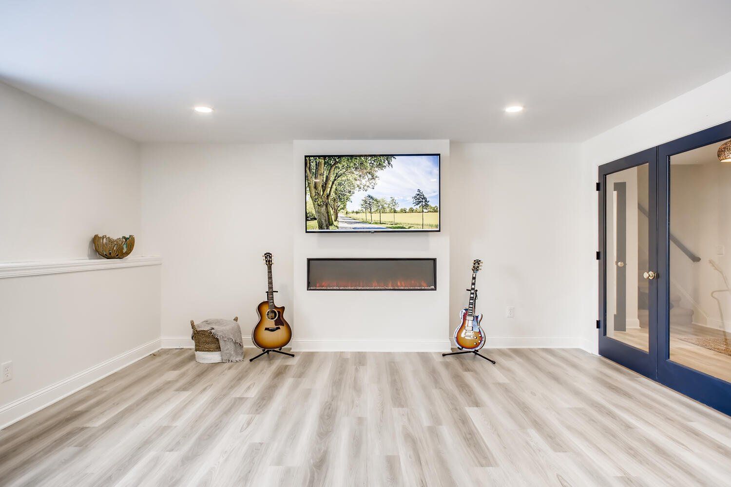 A living room with two guitars and a flat screen tv.