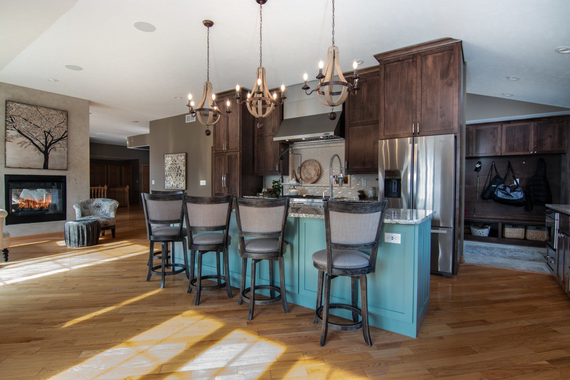 A kitchen with a blue island , stools , a refrigerator , and a fireplace.