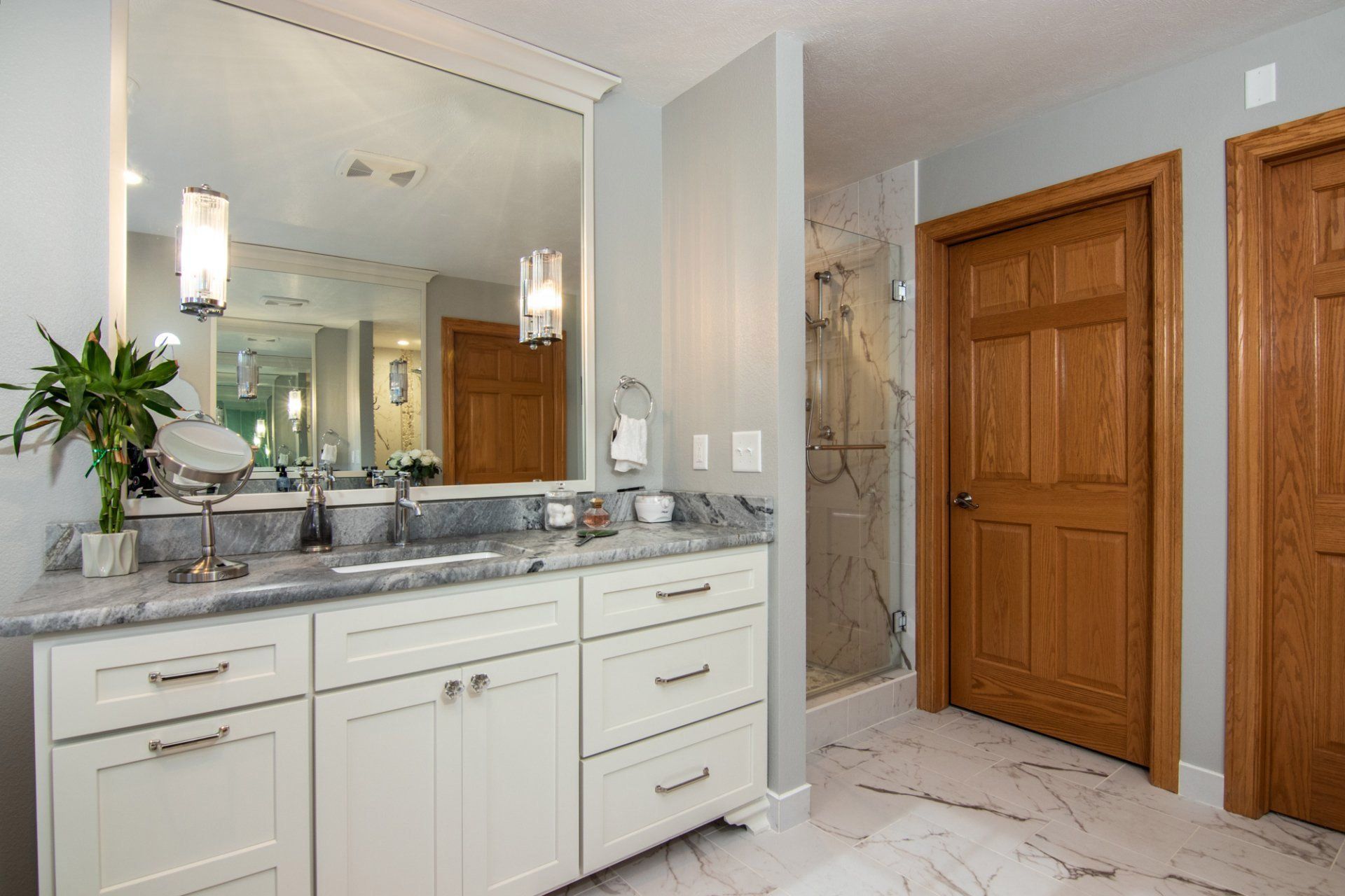A bathroom with two sinks , a large mirror and a walk in shower.