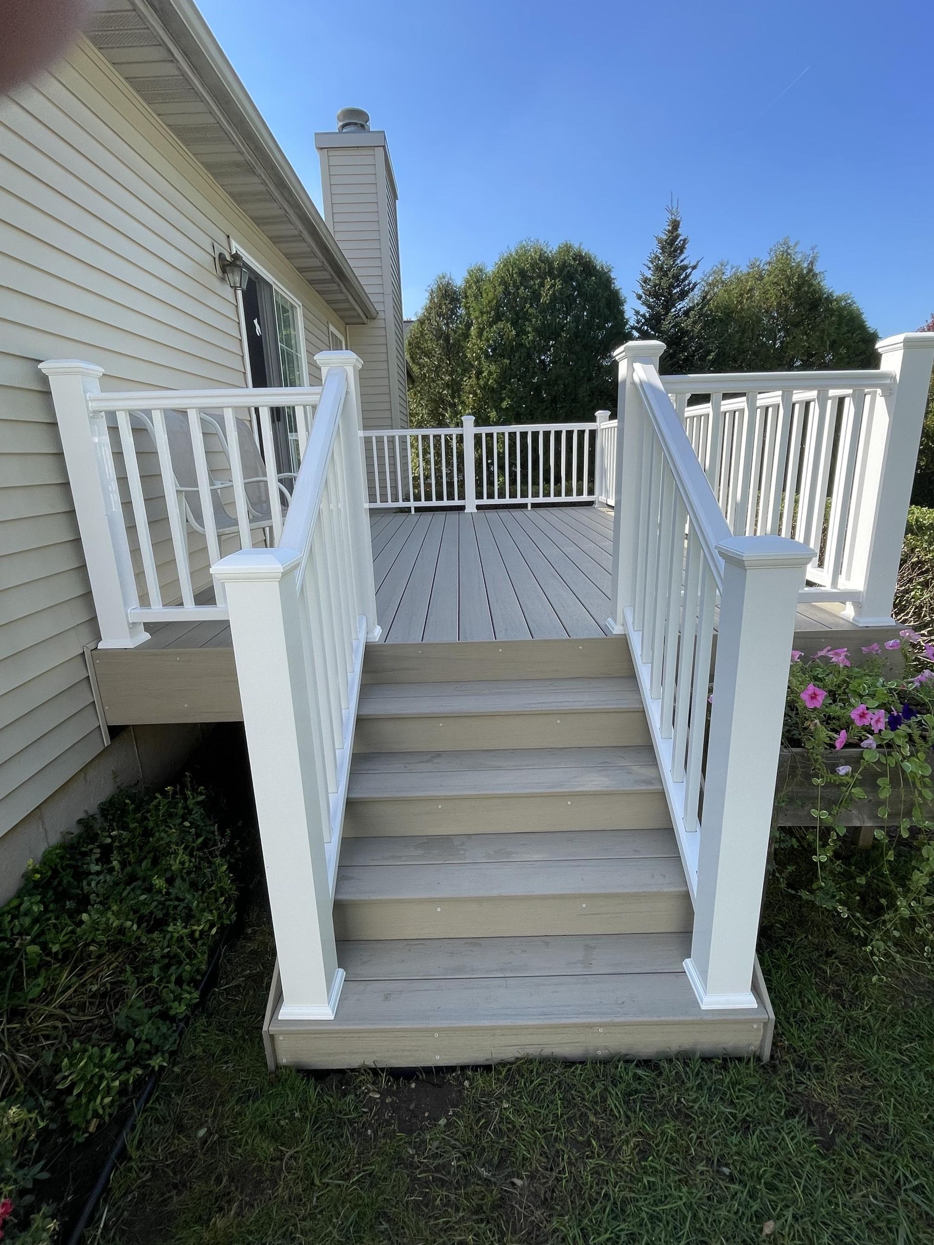 A white deck with stairs leading up to it and a white railing.