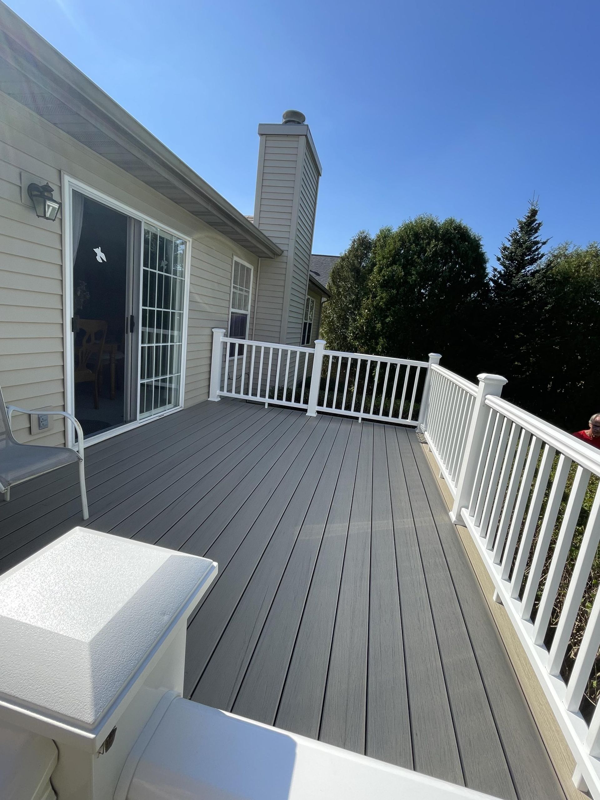 A large deck with a white railing and sliding glass doors