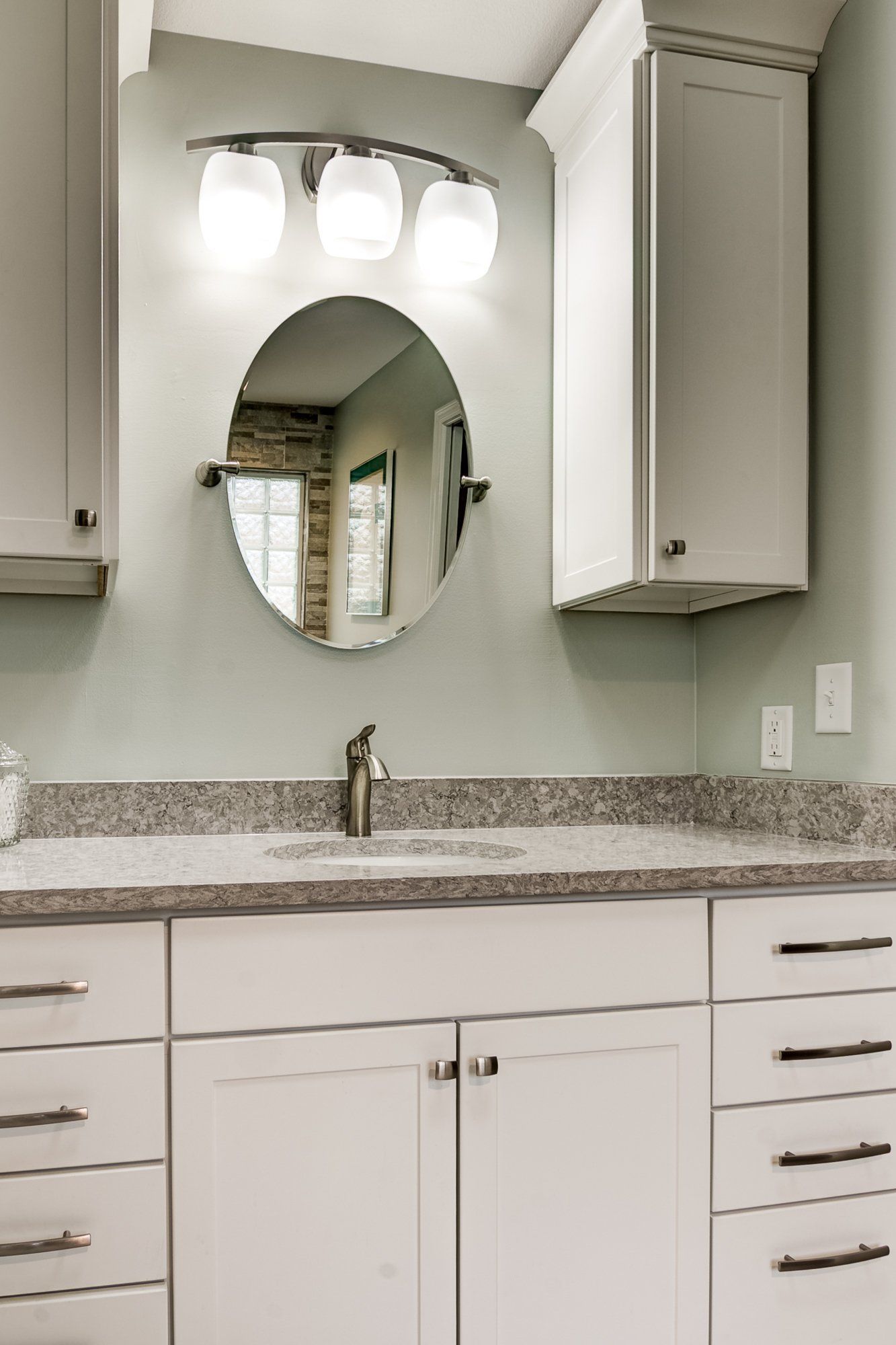 A bathroom with a sink , mirror and cabinets.