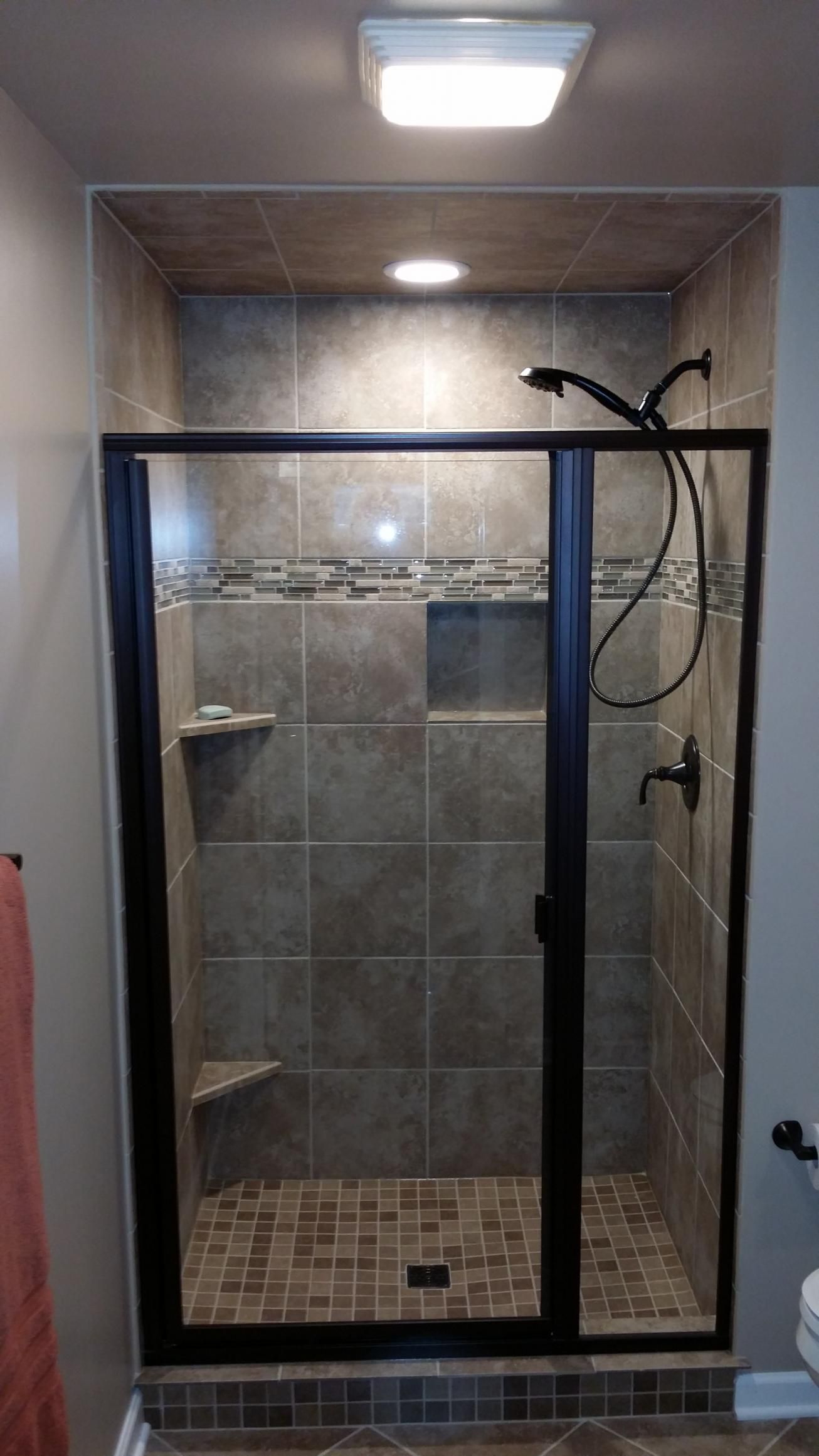 A bathroom with a walk in shower with a glass door and a shower head.