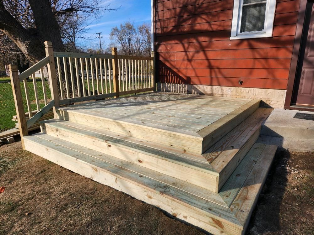 A wooden deck with stairs is in front of a red house.