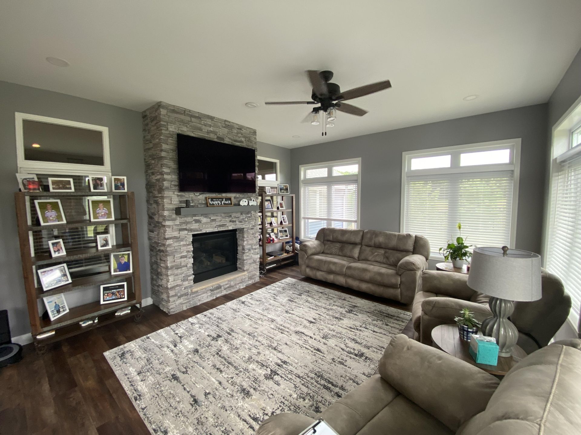 A living room with a couch , chairs , fireplace and television.