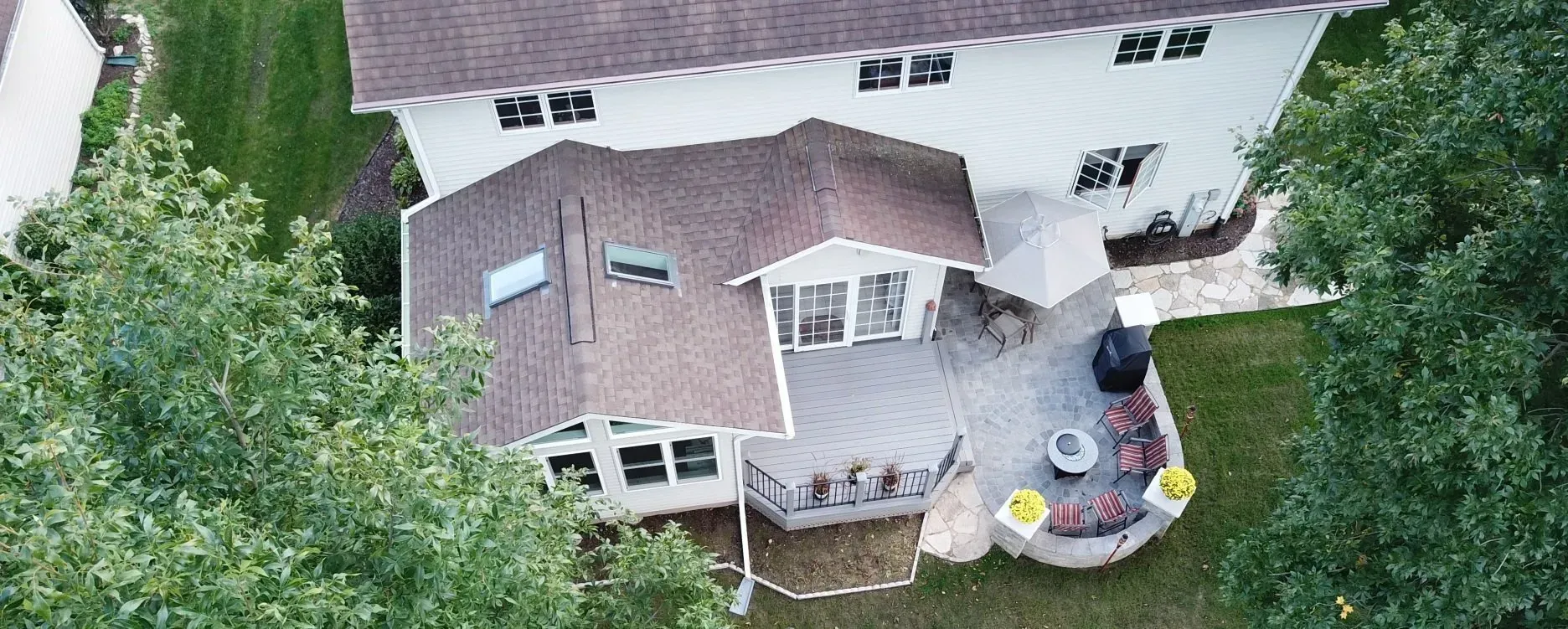 An aerial view of a house with a large deck surrounded by trees.