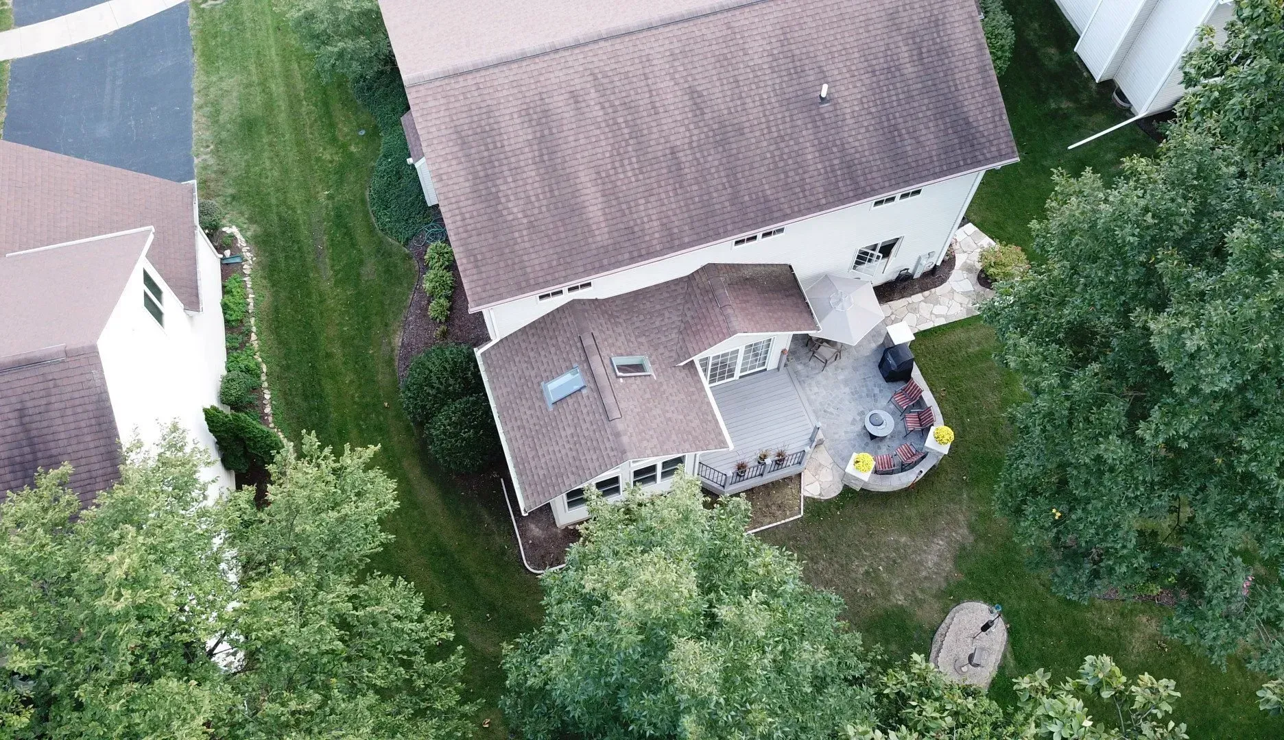 An aerial view of a house in a residential area surrounded by trees.