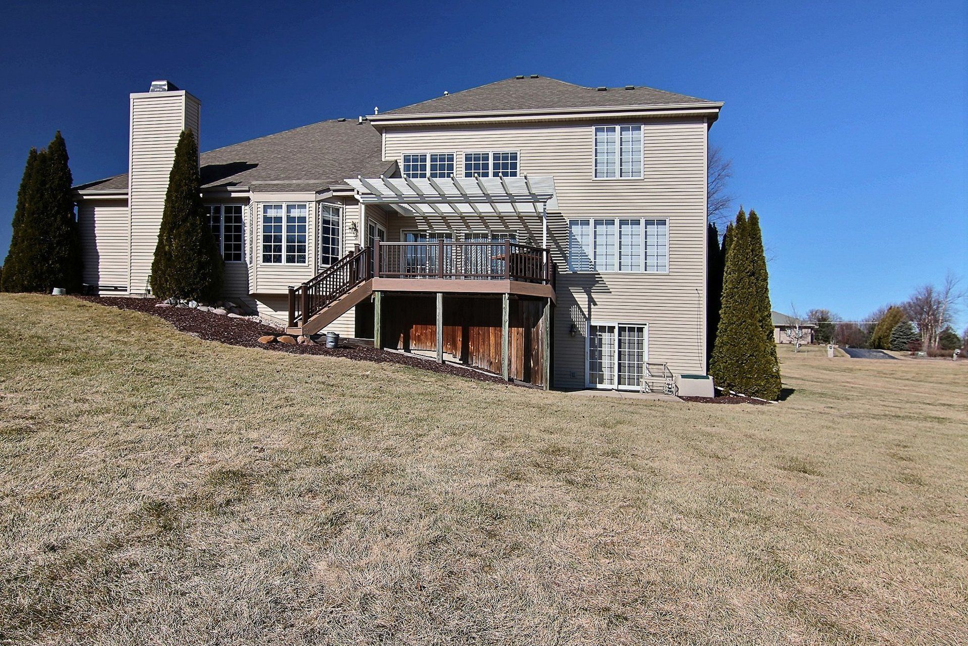 A large house sits on top of a grassy hill
