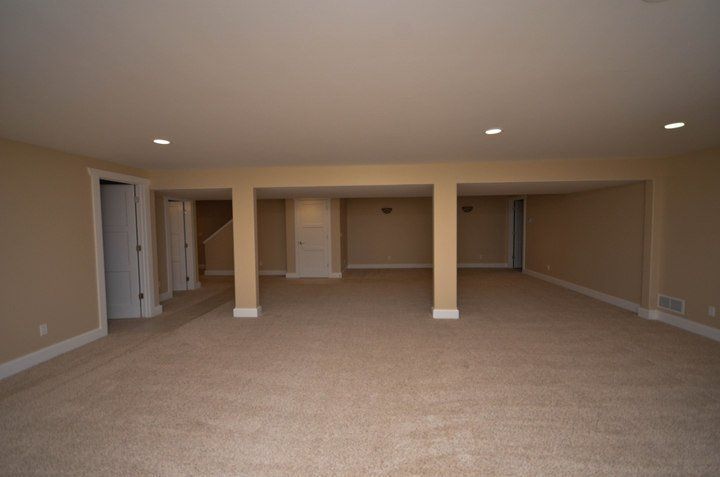 An empty basement with tan walls and tan carpet