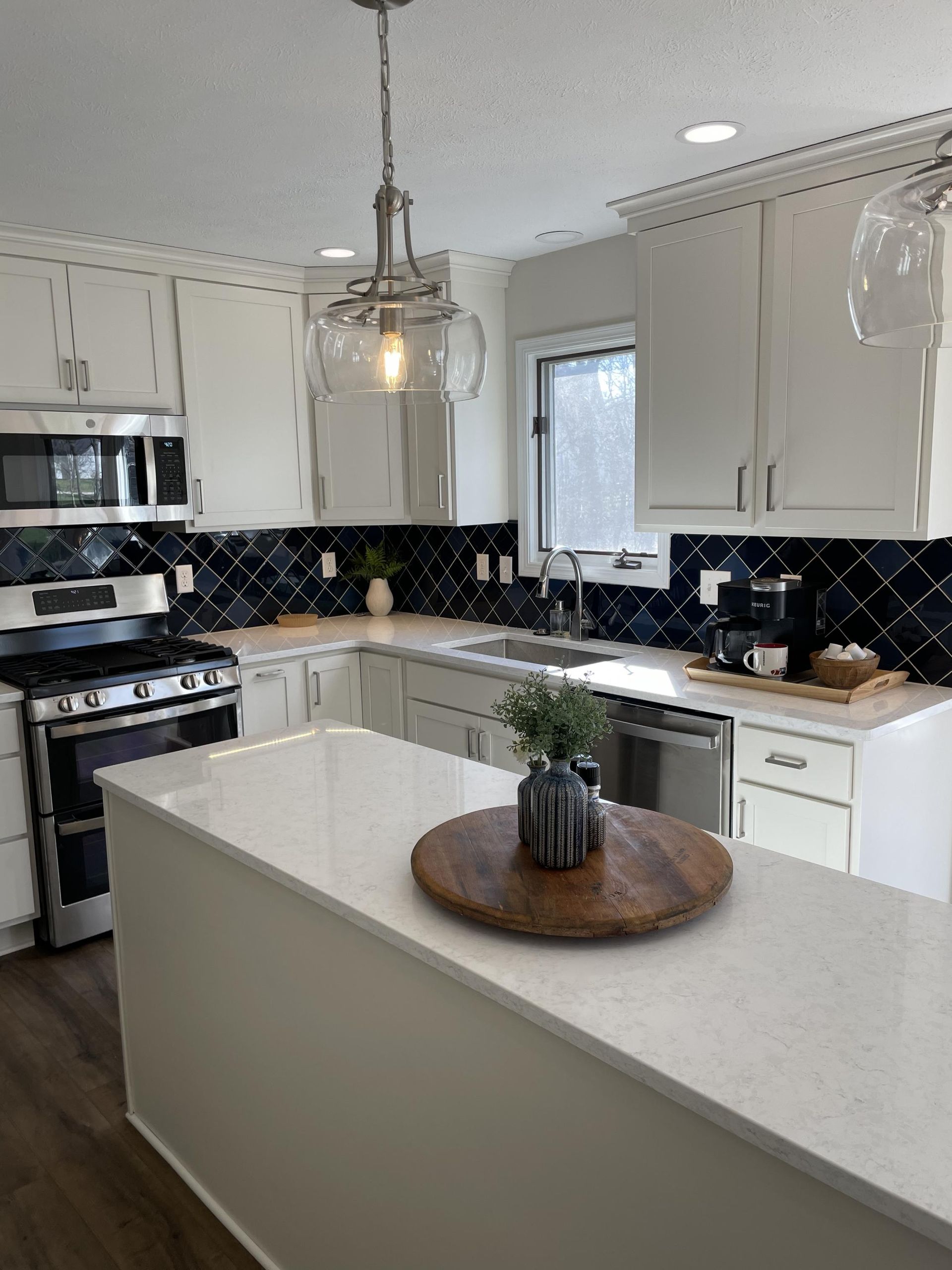 A kitchen with white cabinets , a stove , a sink , and a large island.