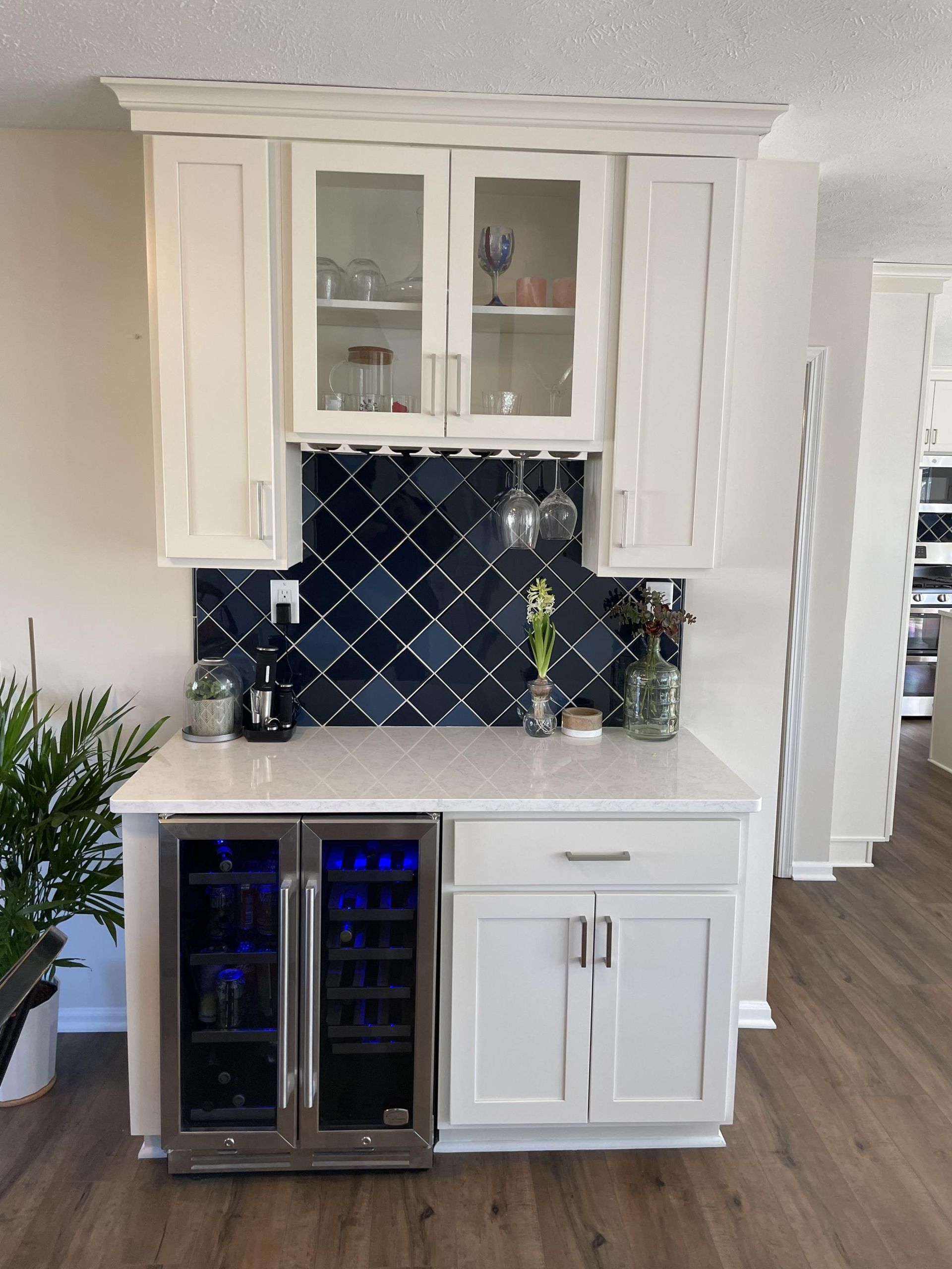 A kitchen with white cabinets and a wine cooler