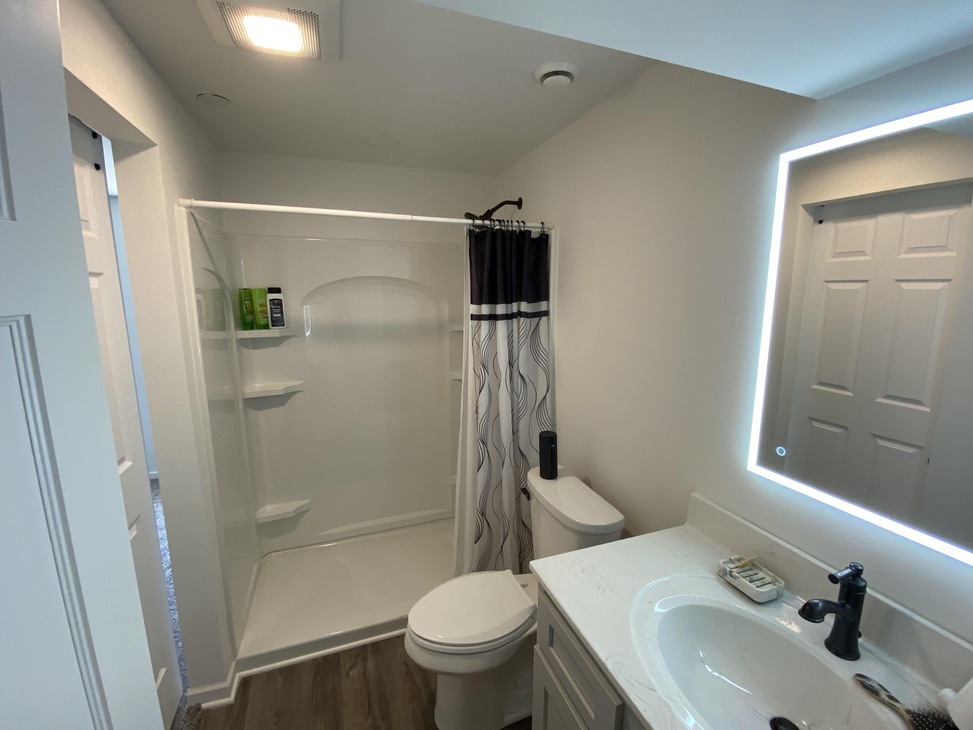A bathroom with a toilet , sink , shower and mirror.