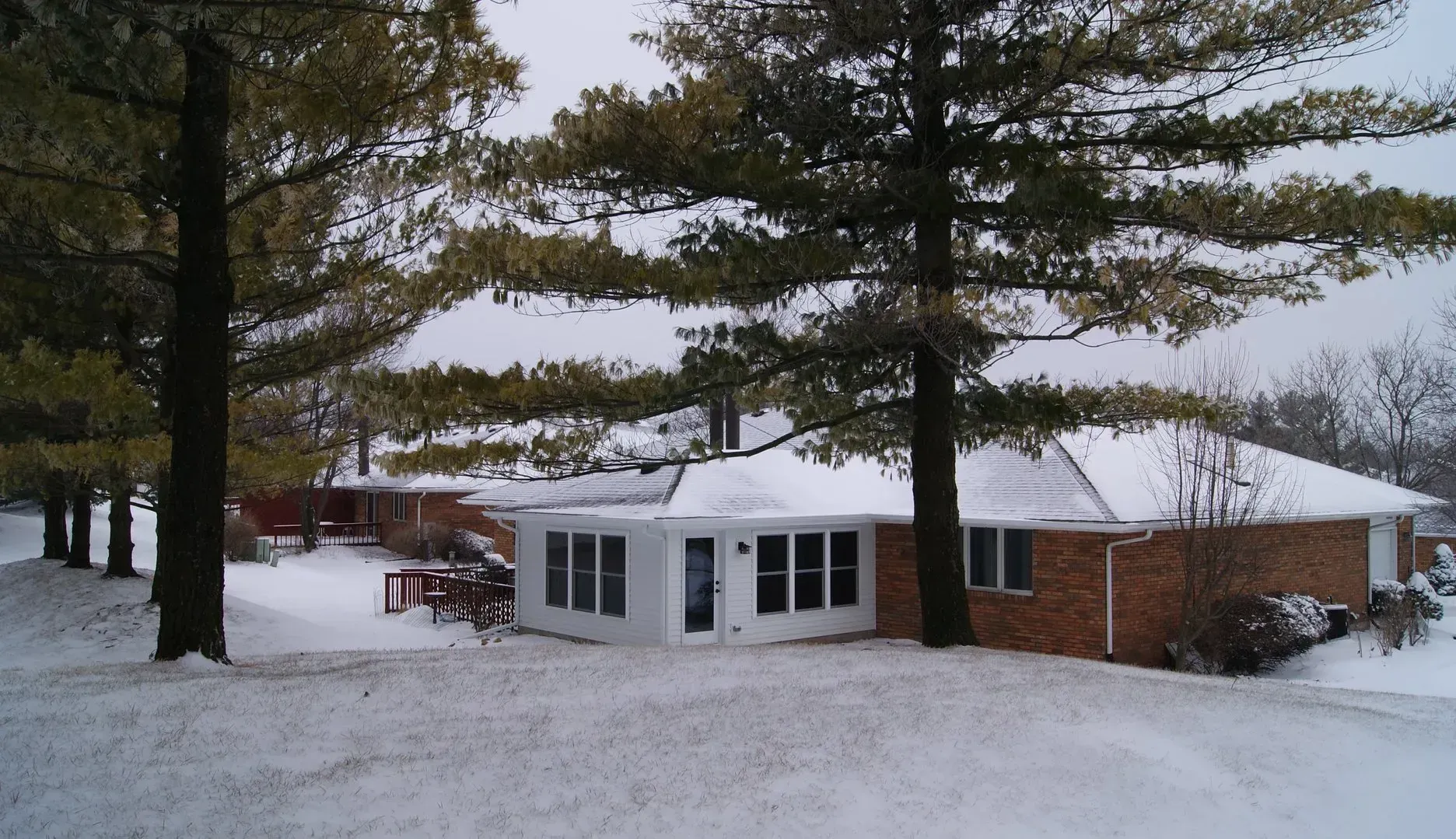 A snowy house with trees in front of it