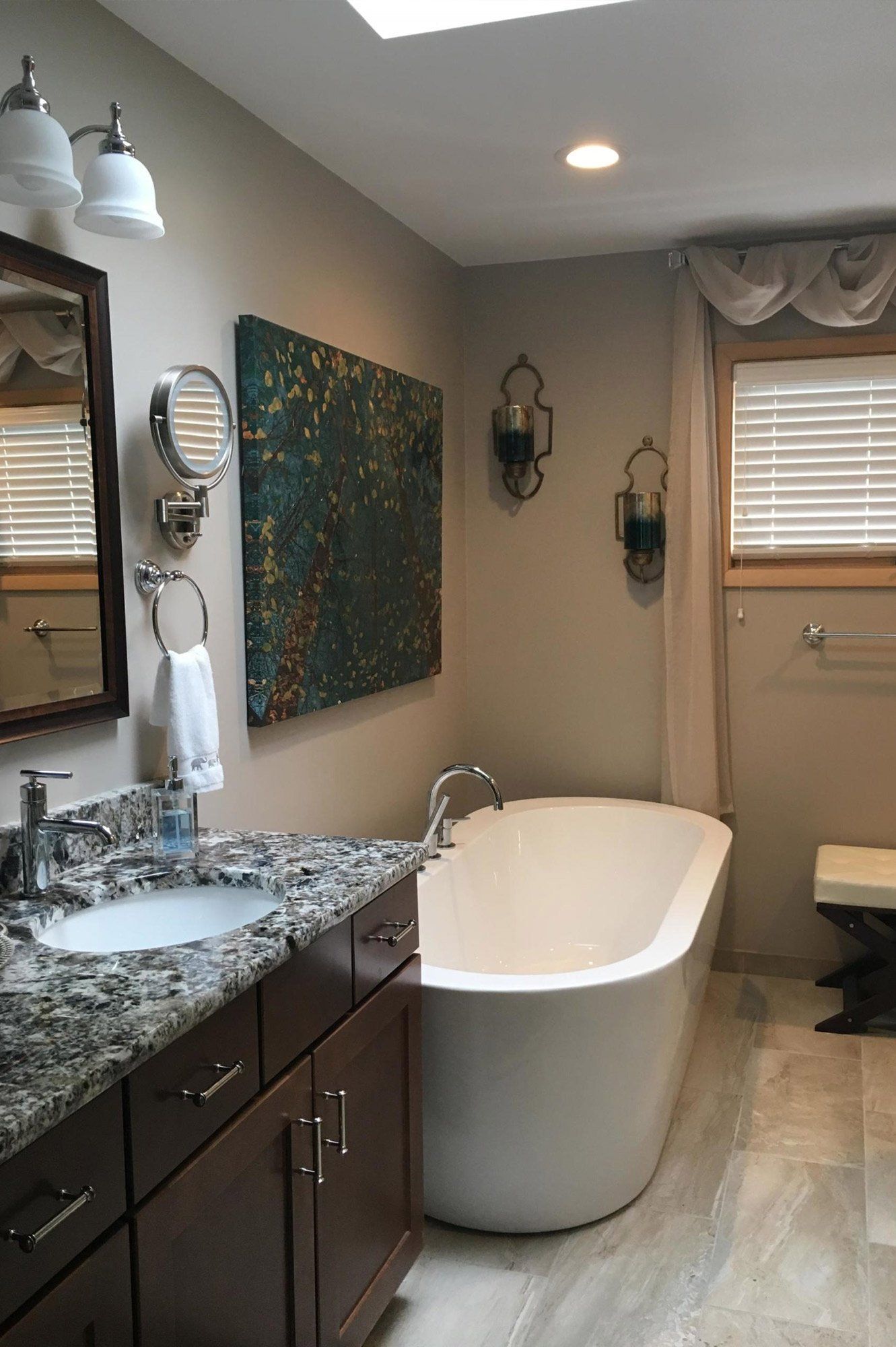 A bathroom with a tub , sink , mirror and skylight.