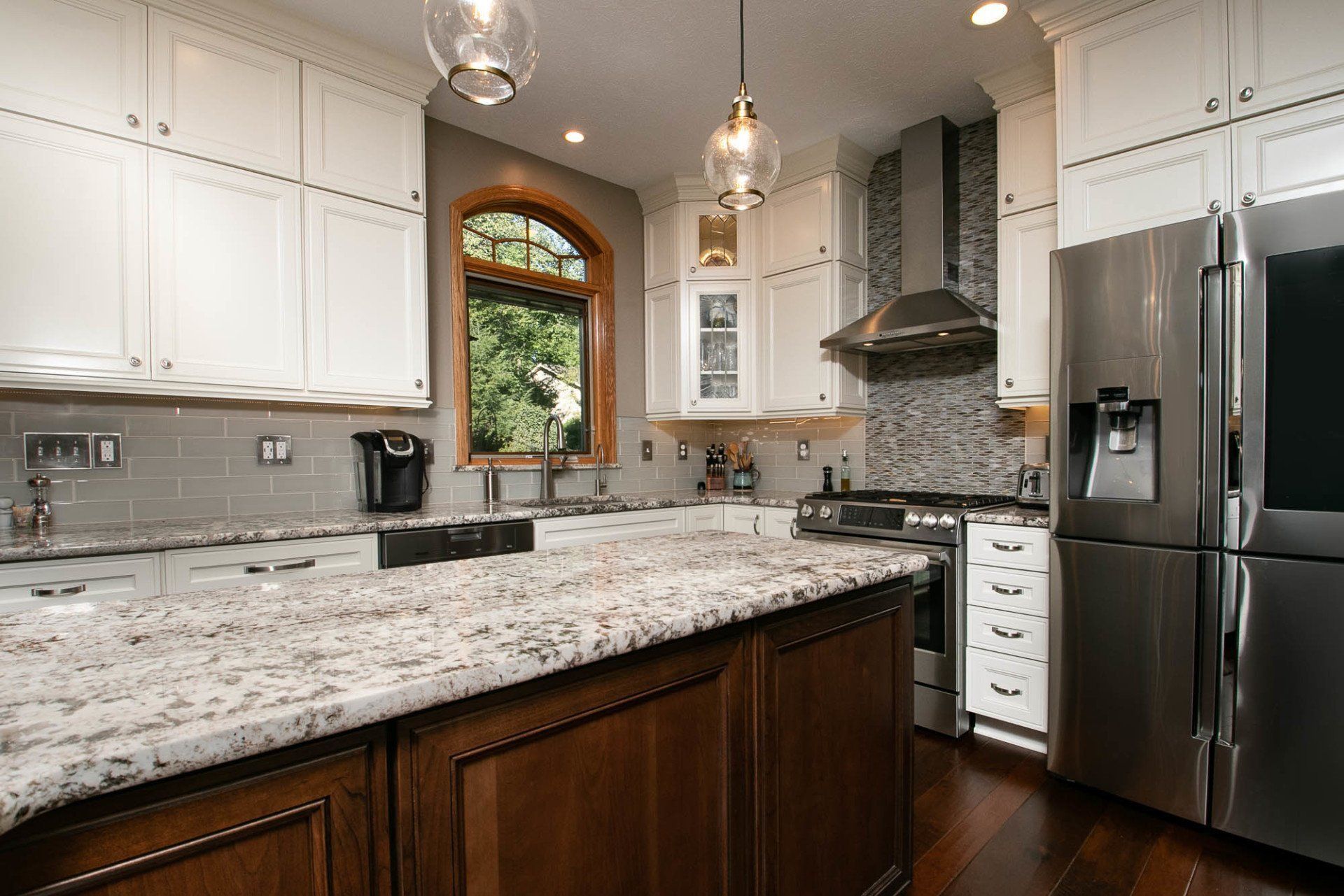 A kitchen with granite counter tops , stainless steel appliances , and white cabinets.